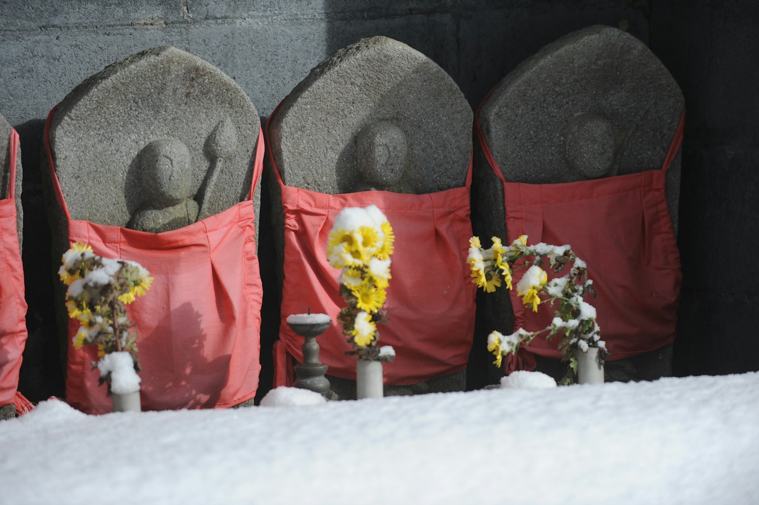 Statue di pietra coperte di neve decorate con fiori