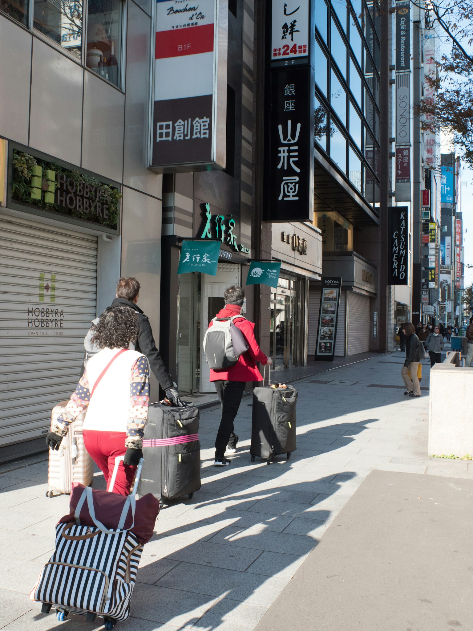 Des personnes marchant avec des bagages dans une rue de Tokyo