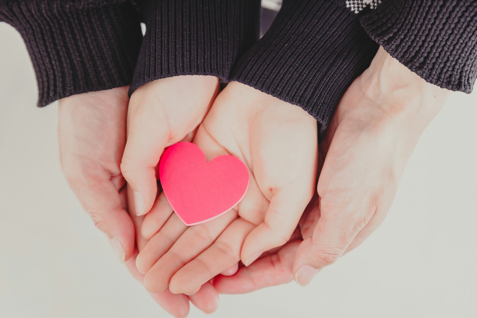 Due mani che tengono un oggetto a forma di cuore rosa
