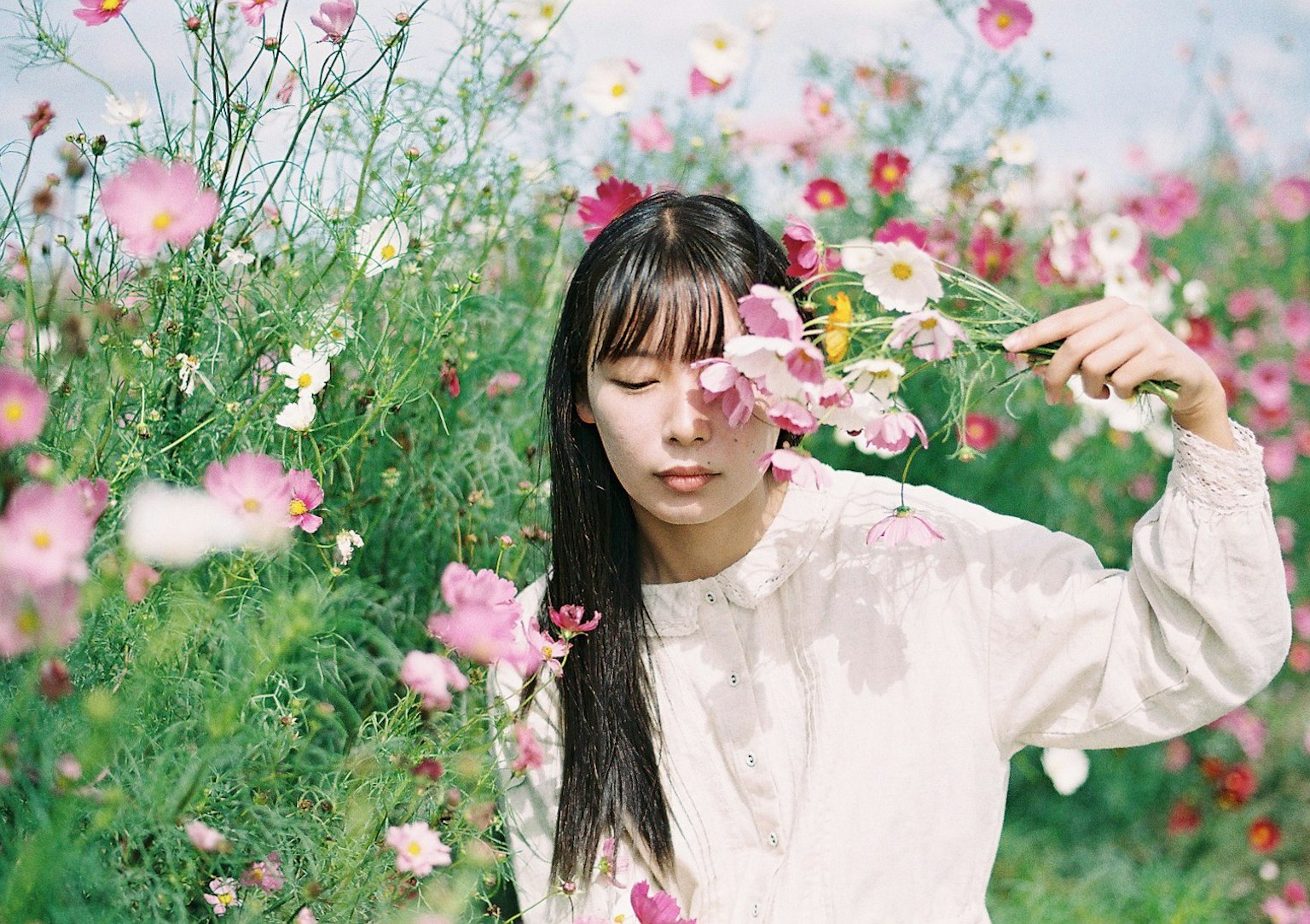Portrait of a woman holding a flower in a field of blossoms