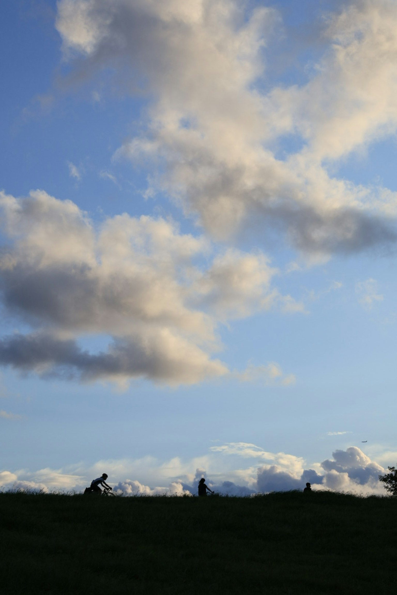 Figures en silhouette marchant sur une colline sous un ciel bleu