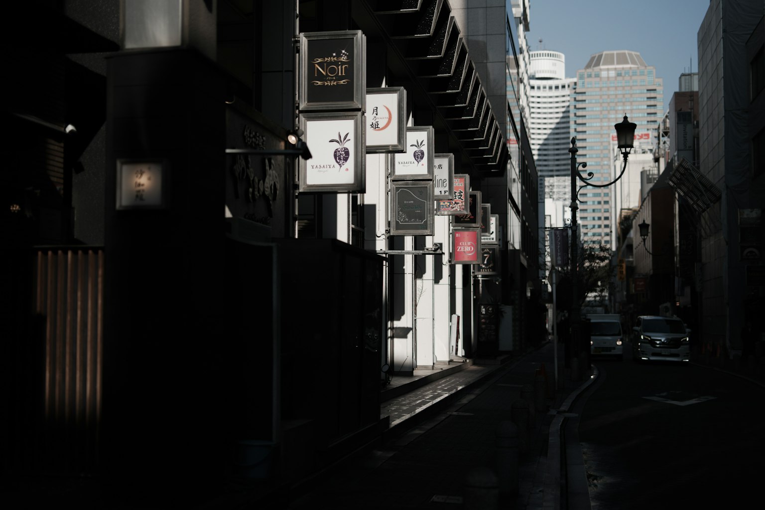 薄暗い通りに並ぶ看板と高層ビルの背景