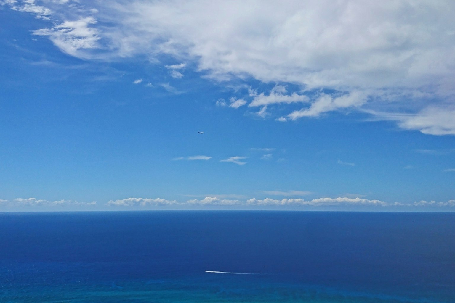 Expansive blue ocean and sky with a distant boat