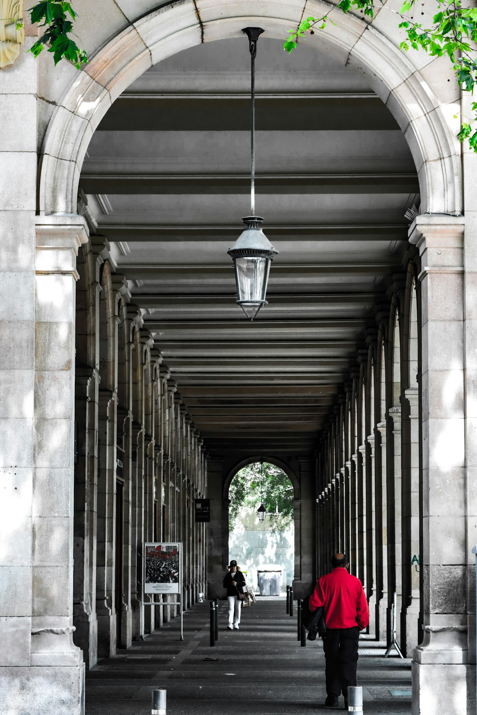 Corridoio ad arco con una persona in cappotto rosso e una lampada appesa