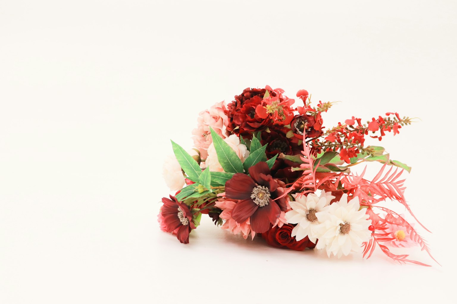 Un arrangement floral avec des fleurs rouges et blanches et des feuilles vertes