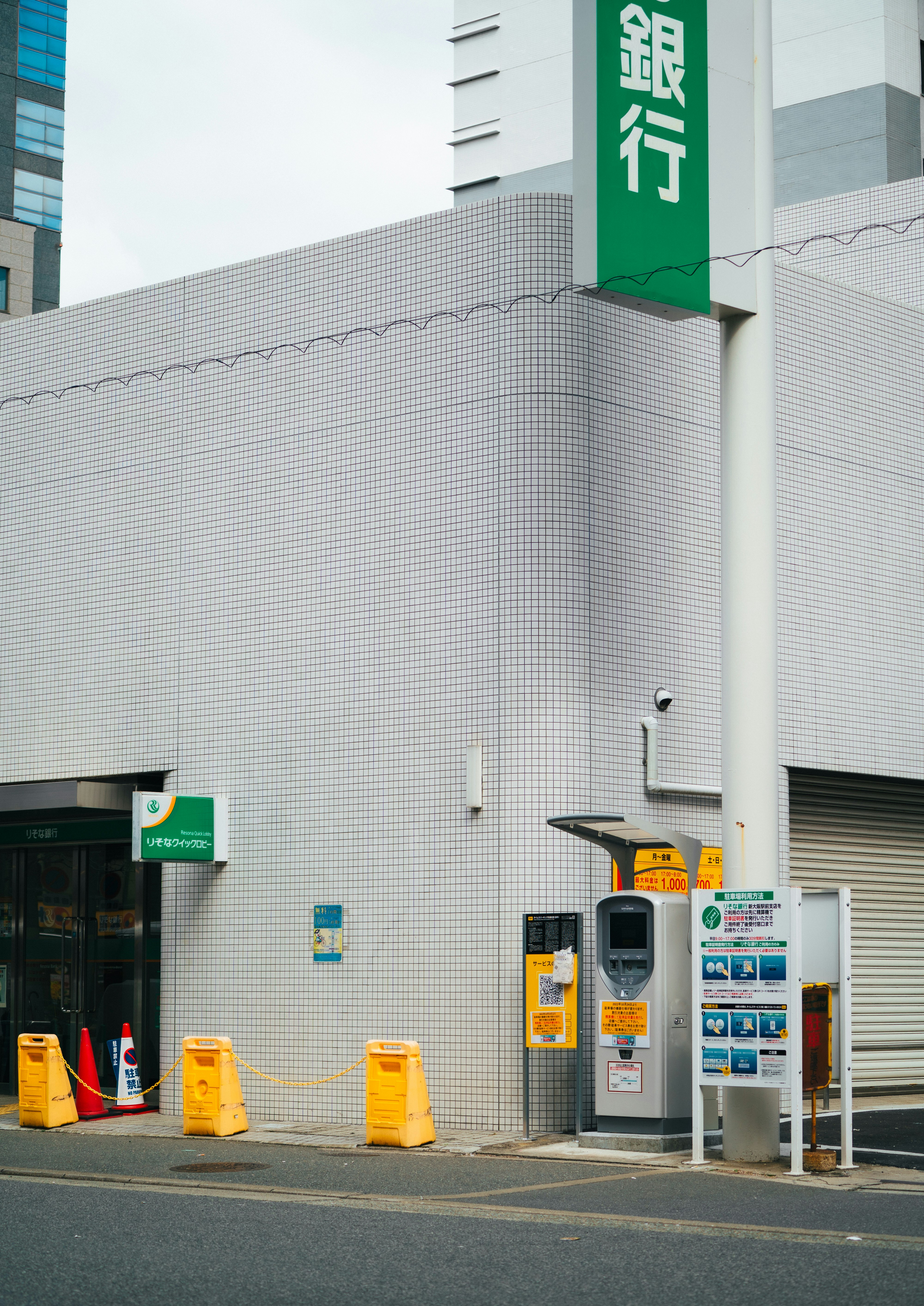 銀行の入口前に並ぶ案内看板と消火器のある街角