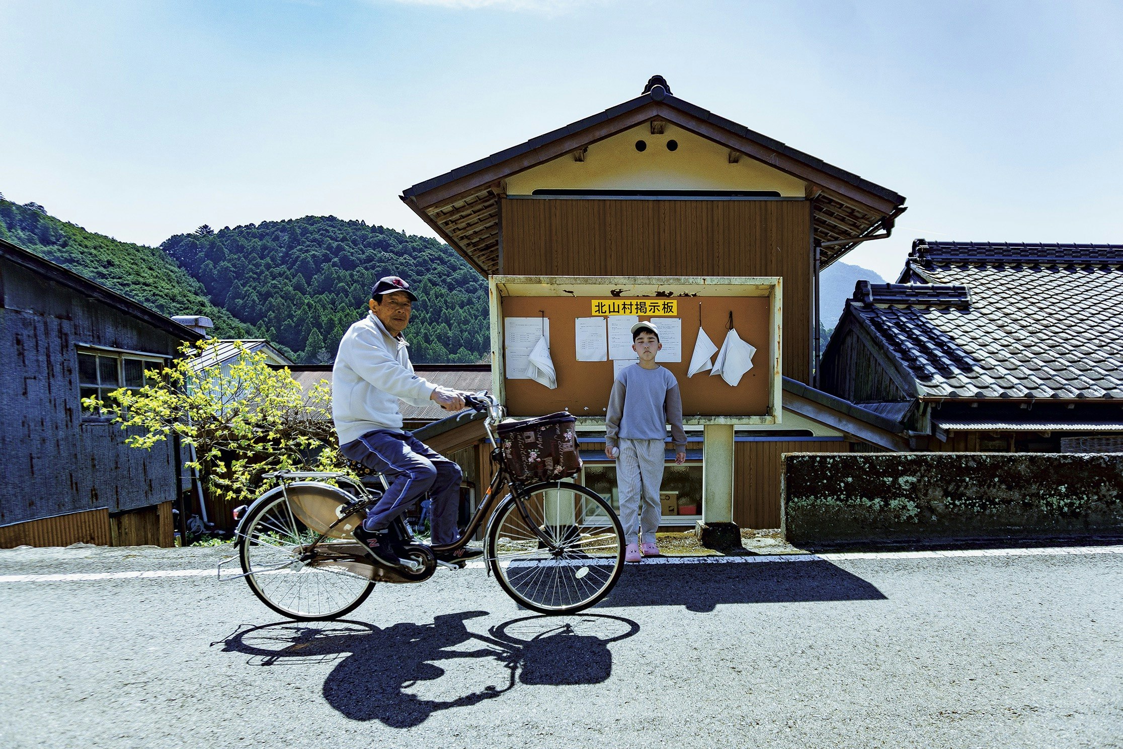 自転車と人が並ぶ田舎の路地の風景