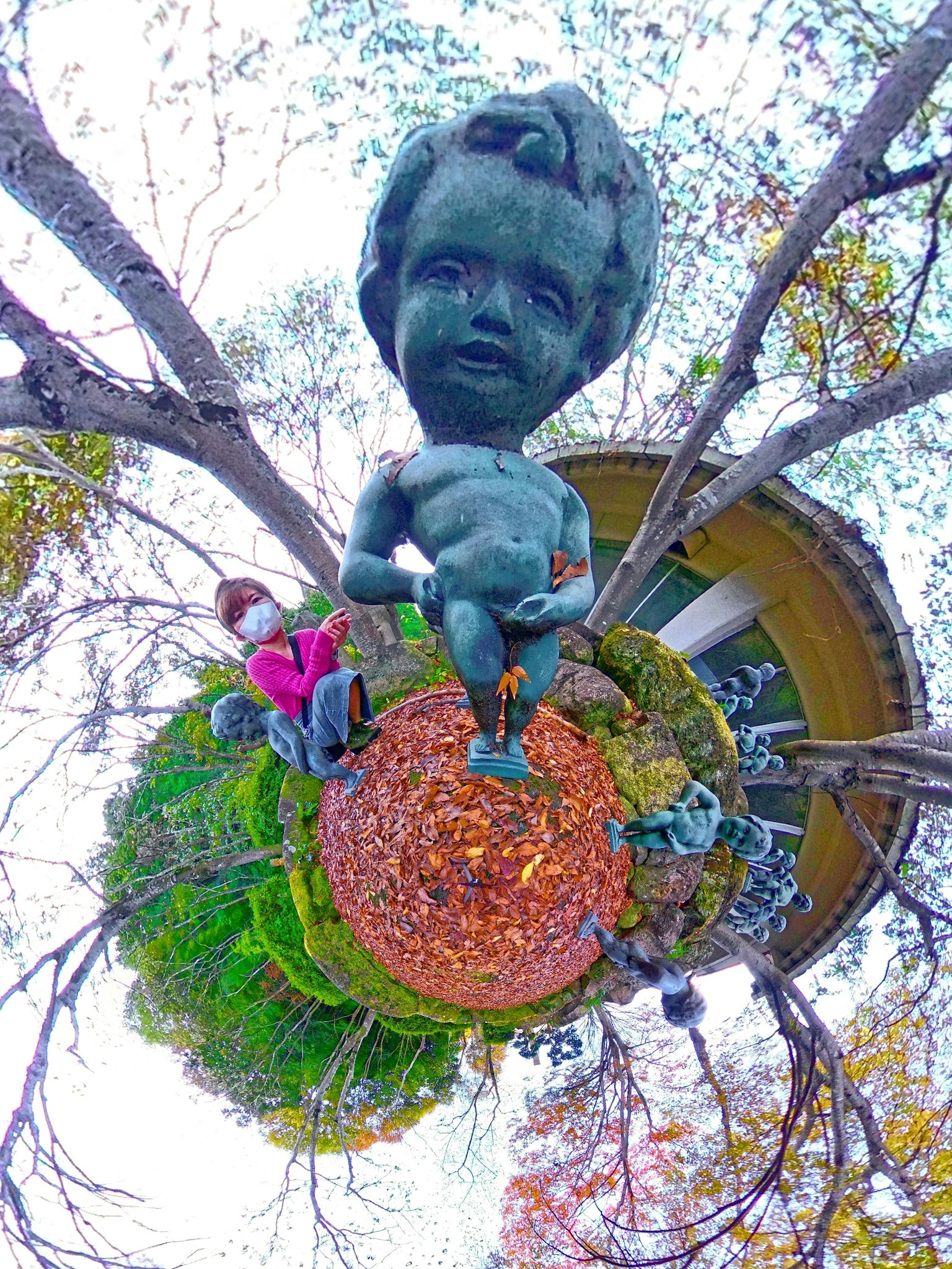 Estatua de niño de bronce en el centro de un jardín con naturaleza circundante