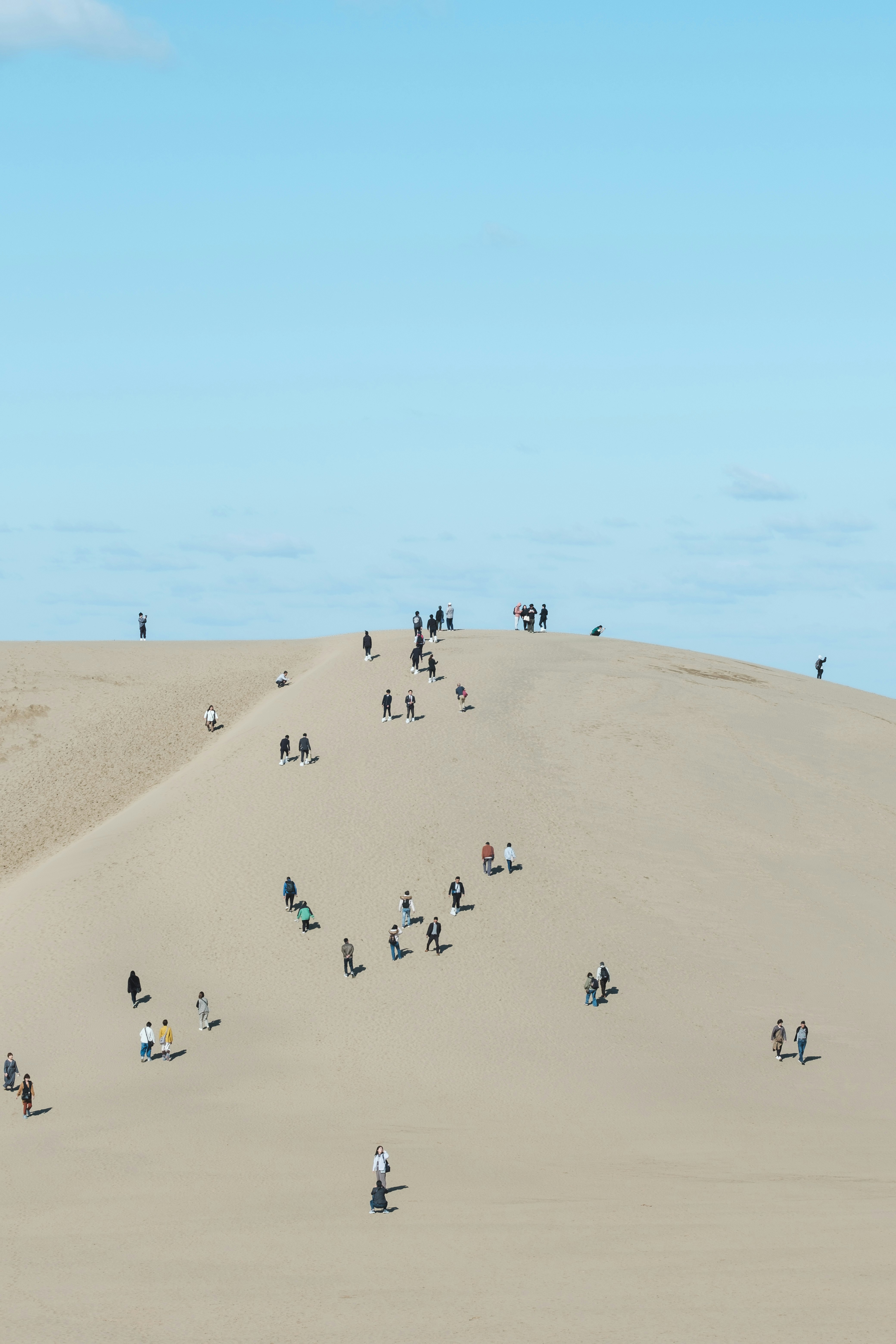 Menschen, die auf einer Sanddüne unter blauem Himmel spazieren
