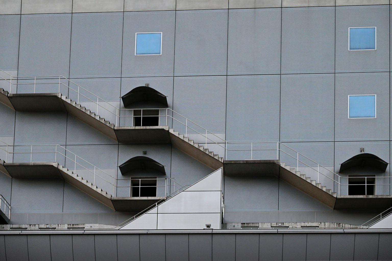Side view of a building with gray walls featuring stairs and windows