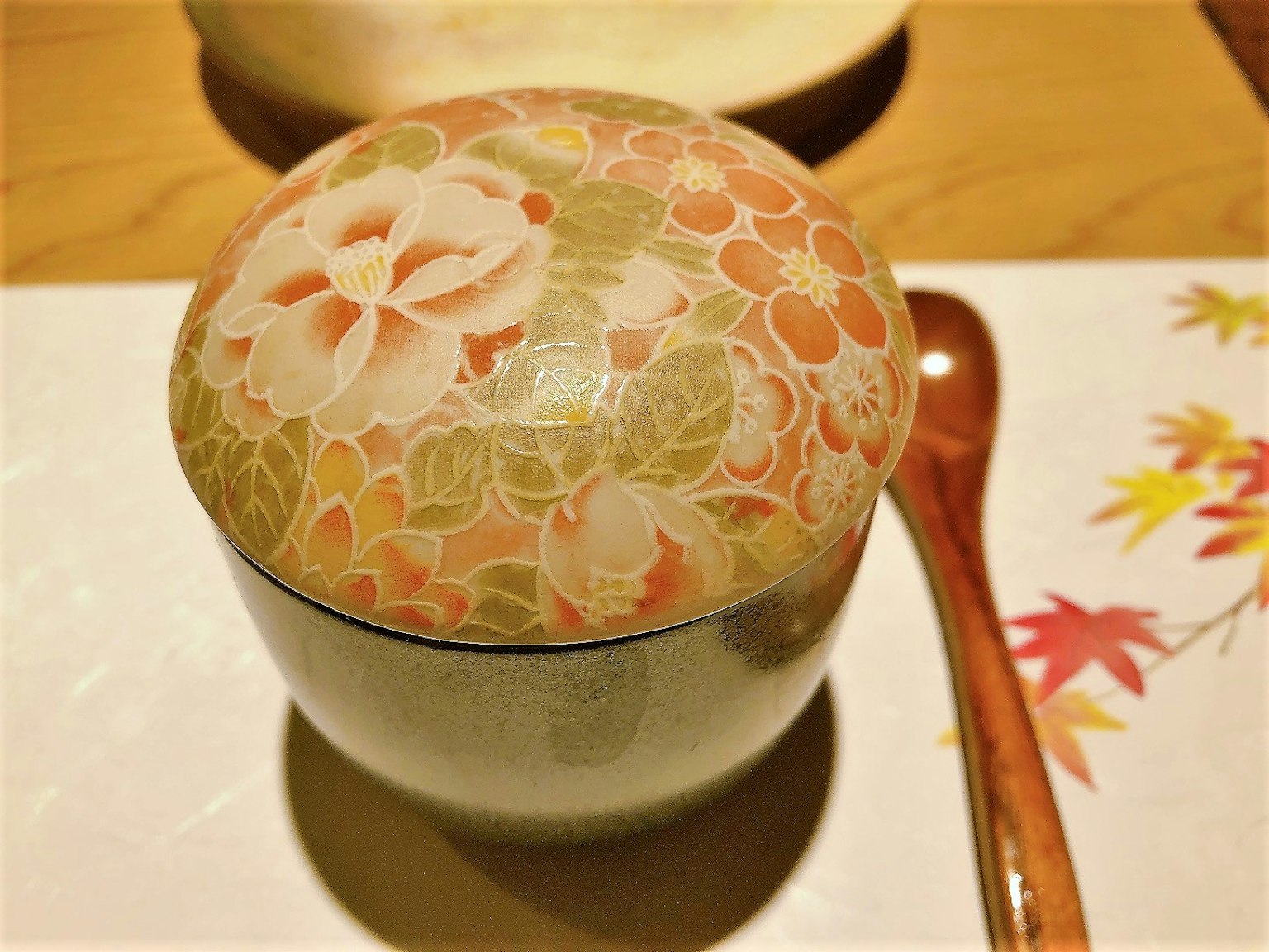 Un bol japonais magnifiquement décoré avec un couvercle floral et une cuillère en bois