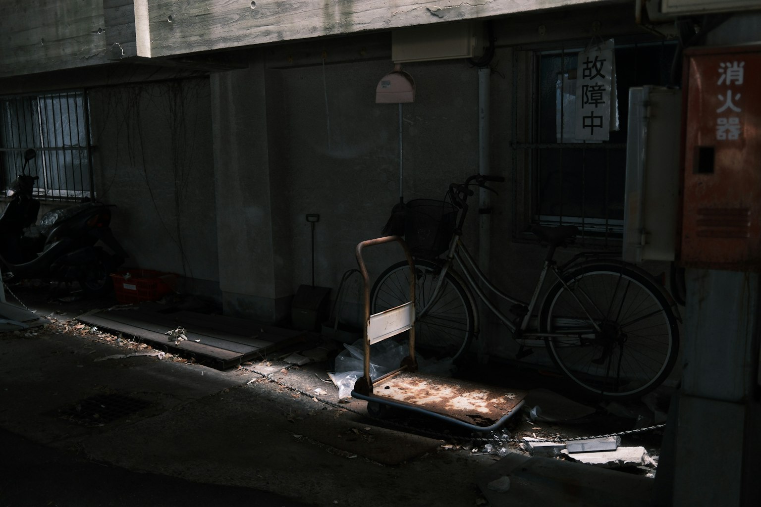 薄暗い路地に置かれた古い自転車と椅子のある風景