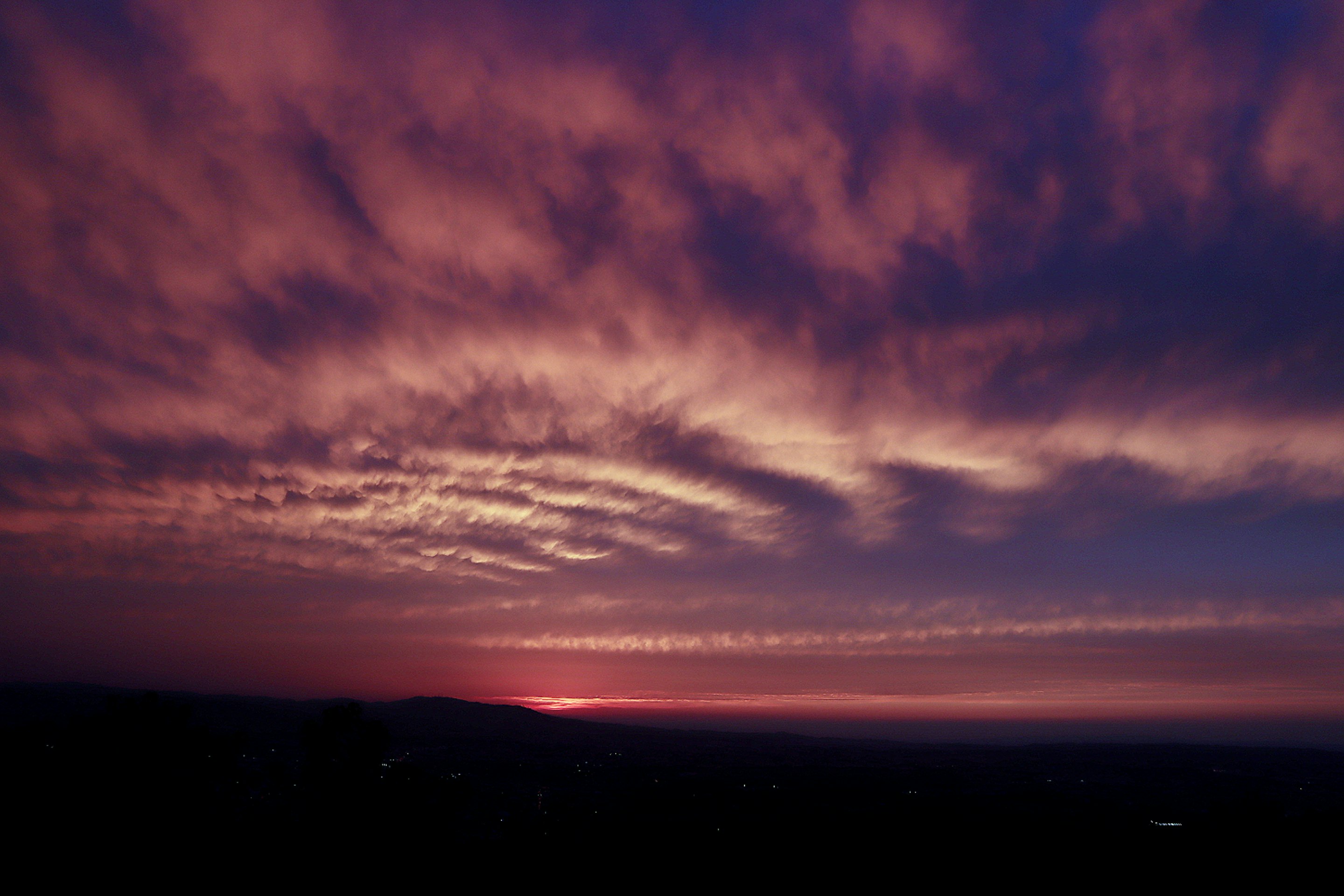 夕焼けの空に広がる雲と地平線のシルエット