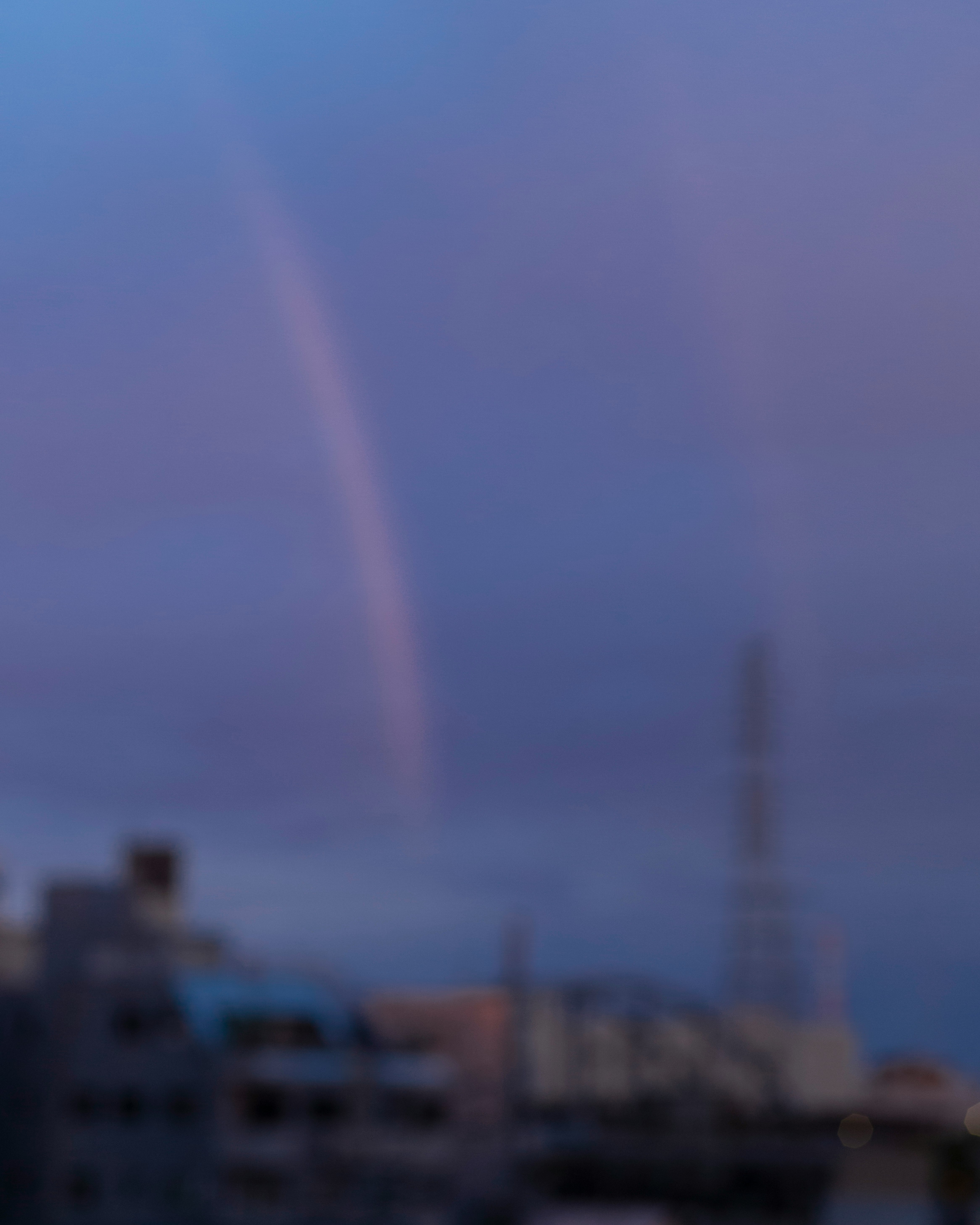 消えゆく虹がかかる夕暮れの空と街並み