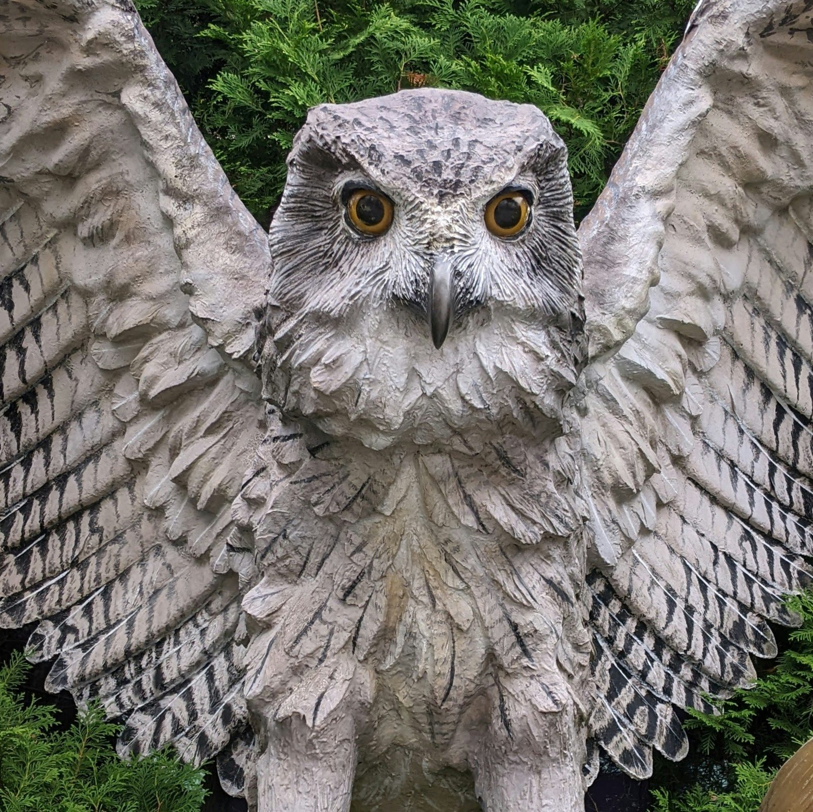 estatua de búho de piedra con las alas extendidas sobre un muro de jardín