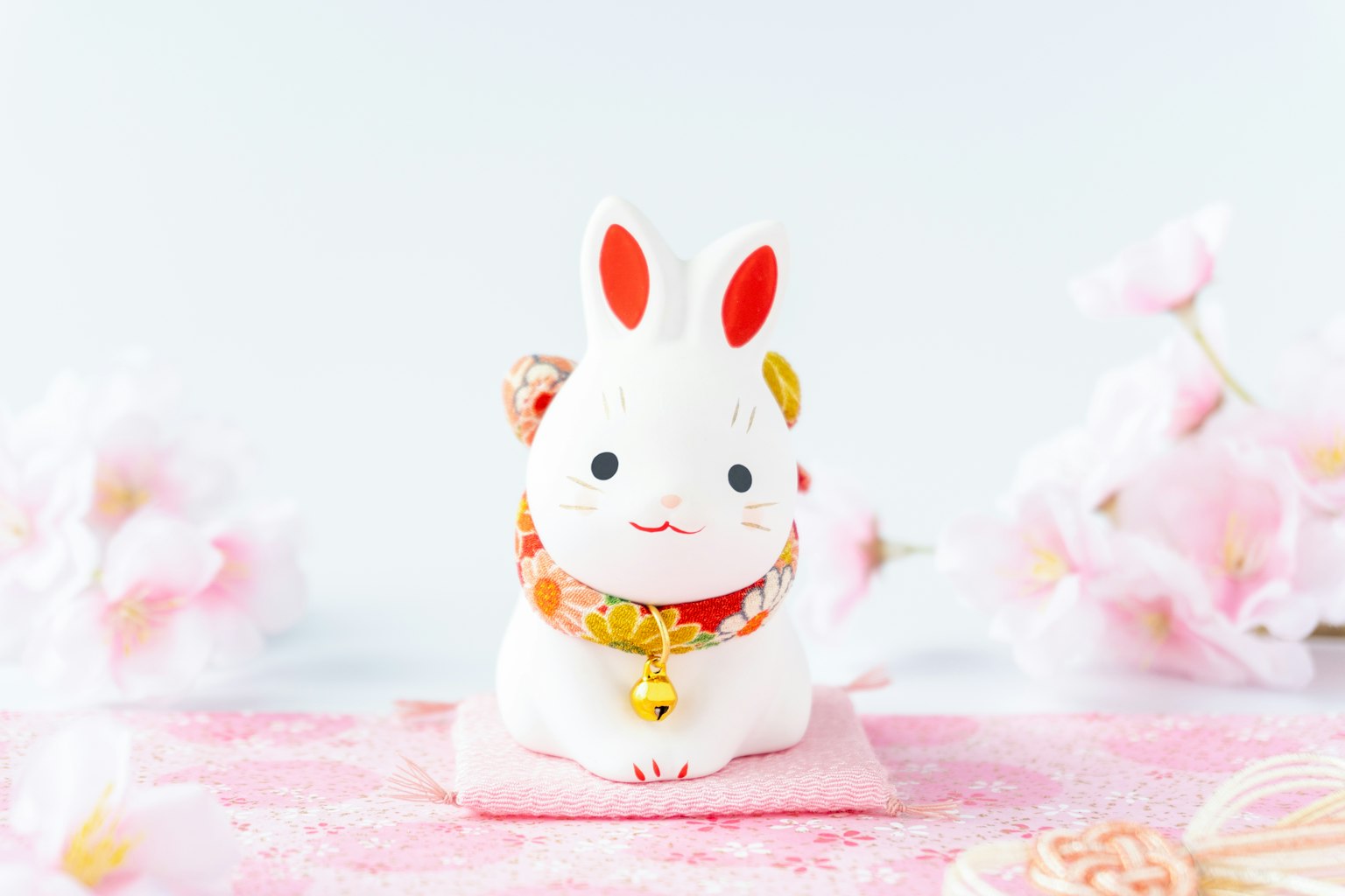 Weiße Kaninchenfigur umgeben von Kirschblüten