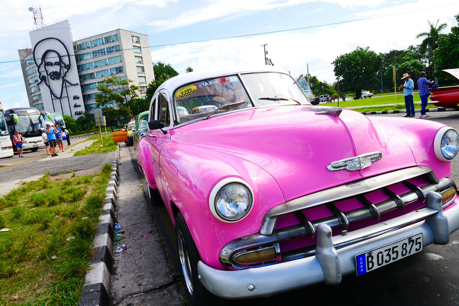 Ein lebendiges pinkes Oldtimer mit einem Graffiti-Gebäude im Hintergrund