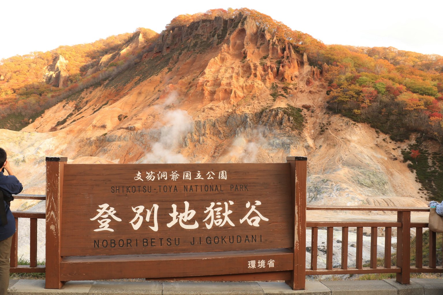Cartel de la Valle del Infierno de Noboribetsu con montañas circundantes