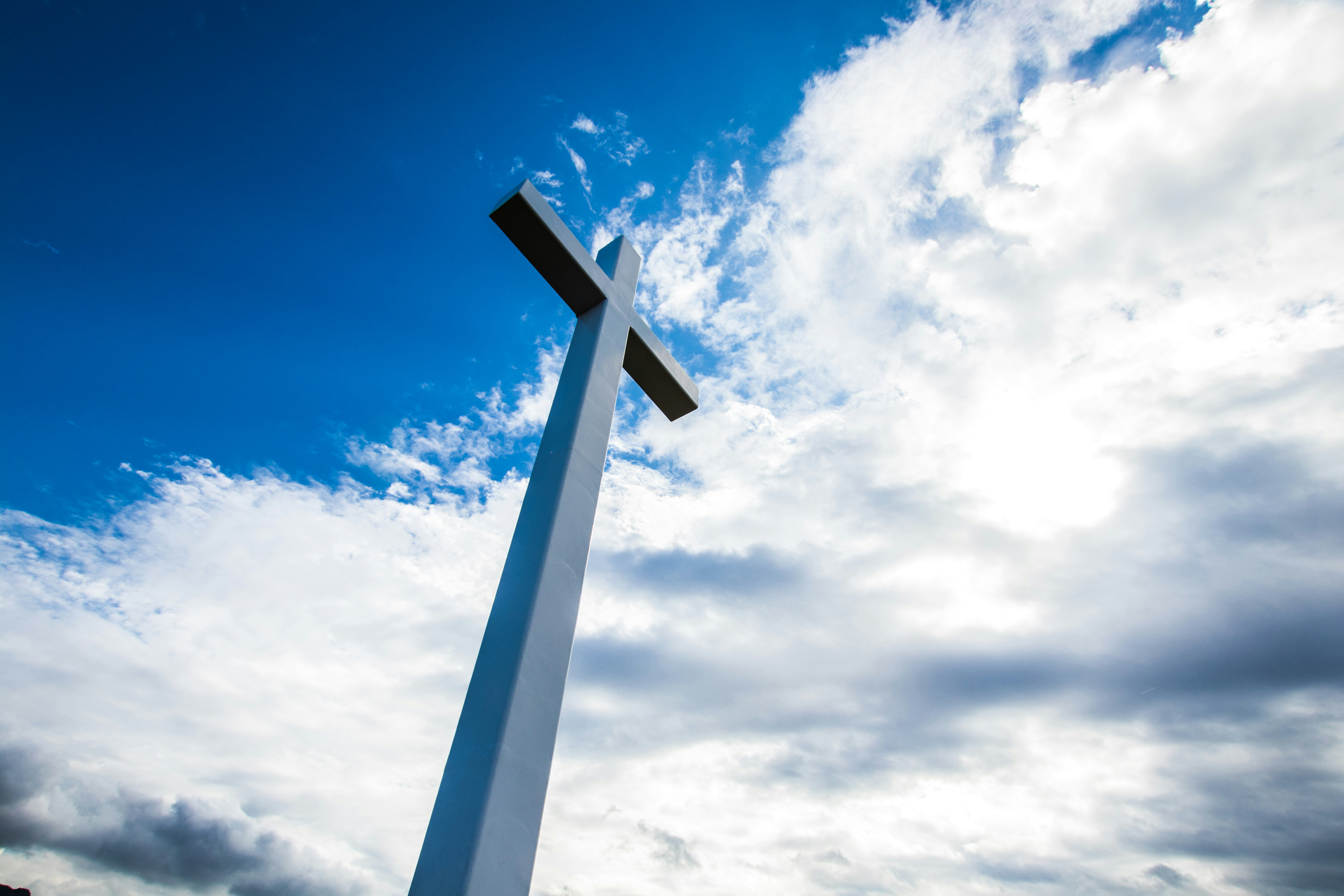 cross silhouette against blue sky and clouds