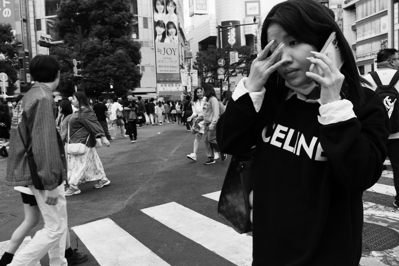 Photo en noir et blanc d'une femme tenant un téléphone au carrefour de Shibuya