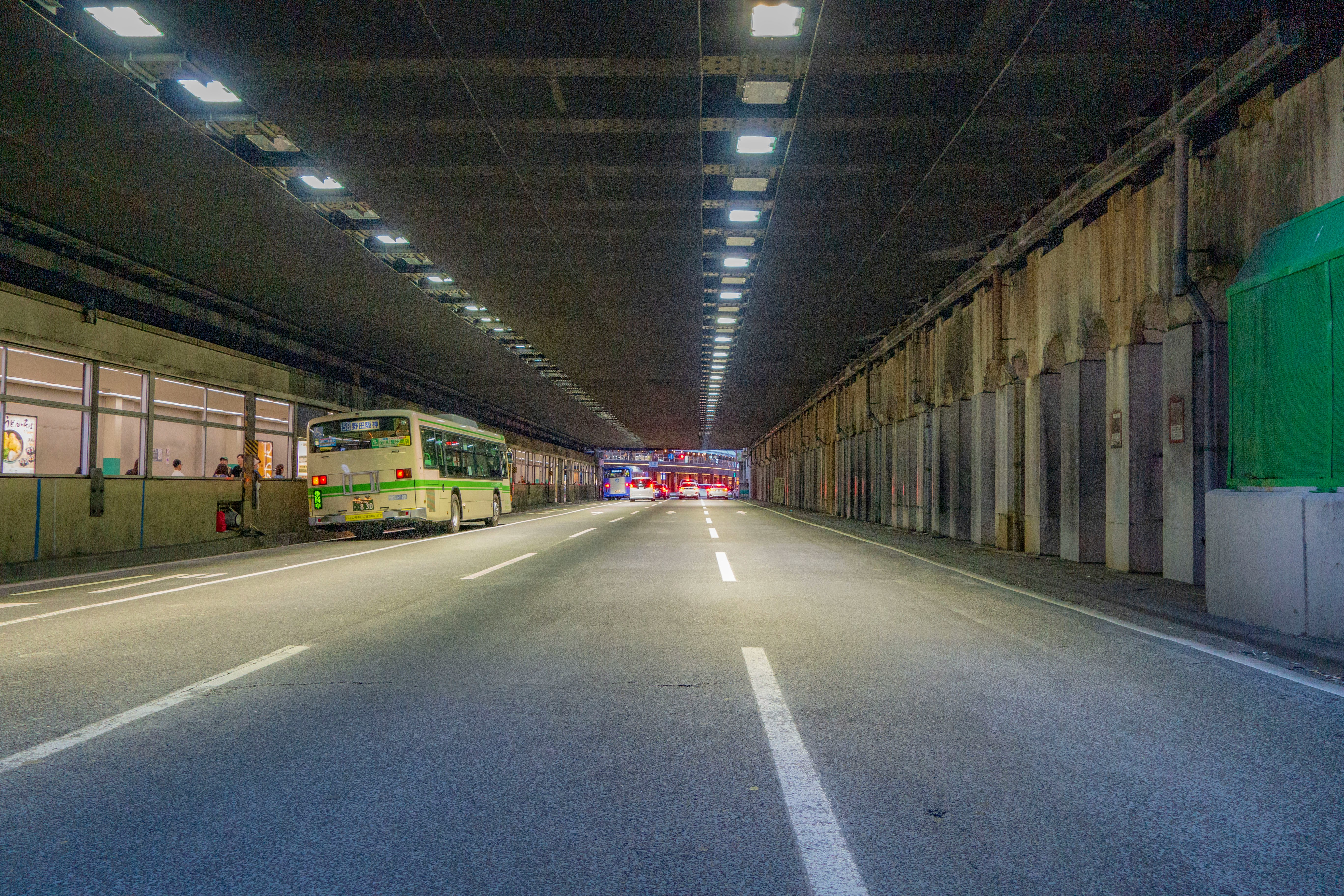 高架下の長い車道と壁面のシャッターが続くトンネル風の通路