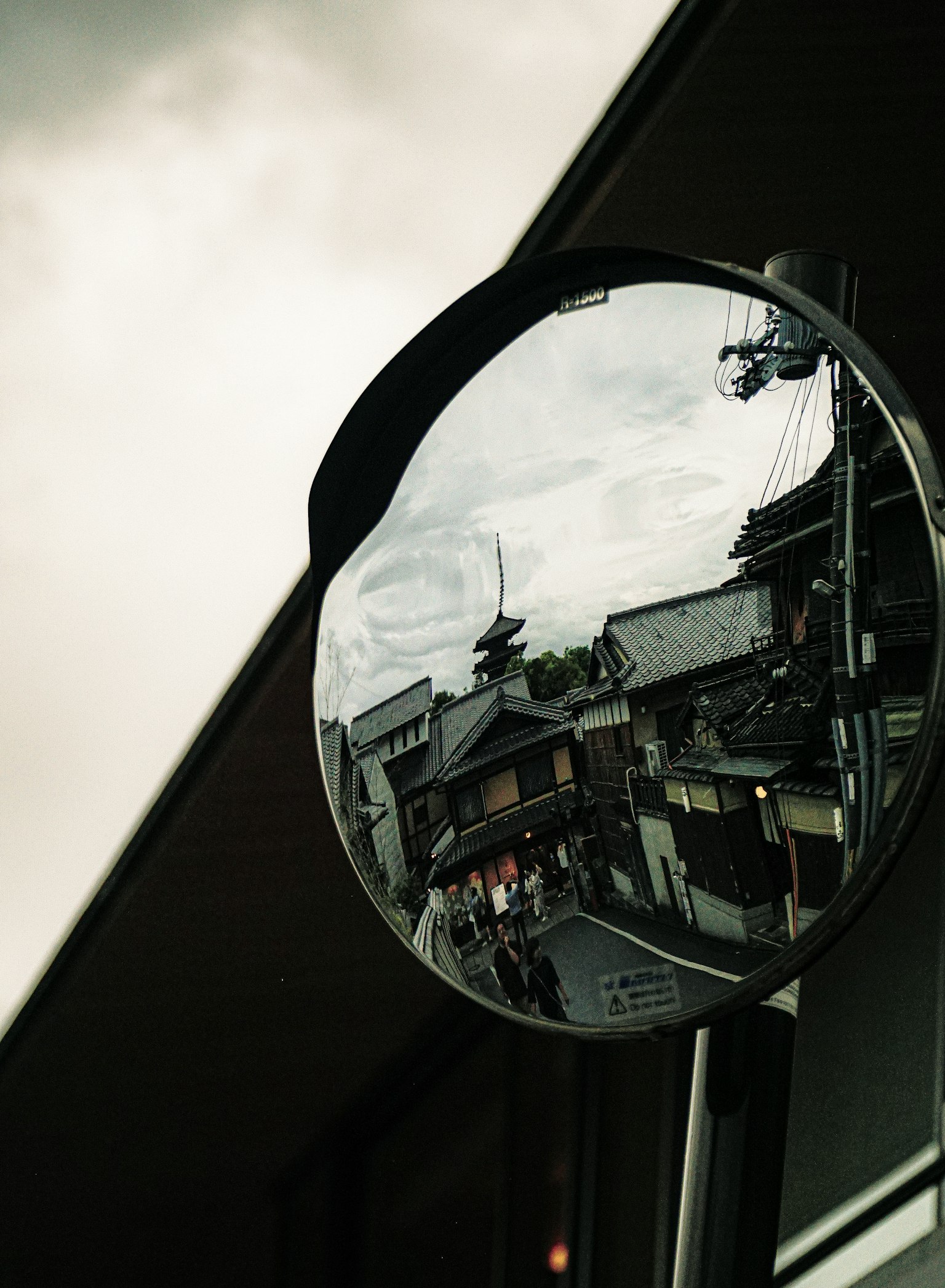 Miroir rond reflétant un paysage urbain sous un ciel nuageux