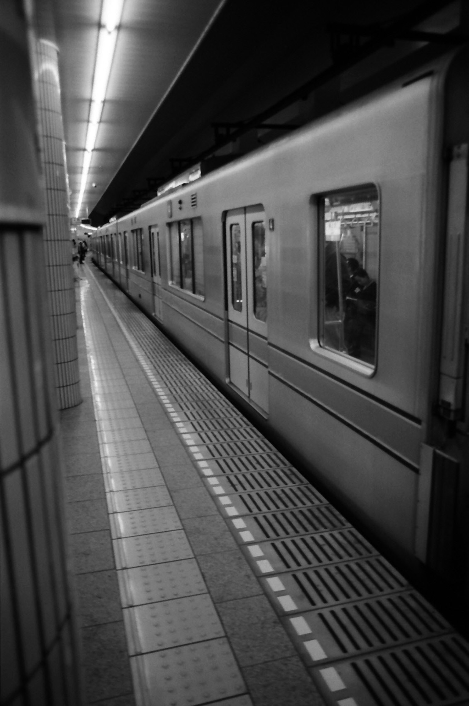 Immagine in bianco e nero di una piattaforma della metropolitana con un treno