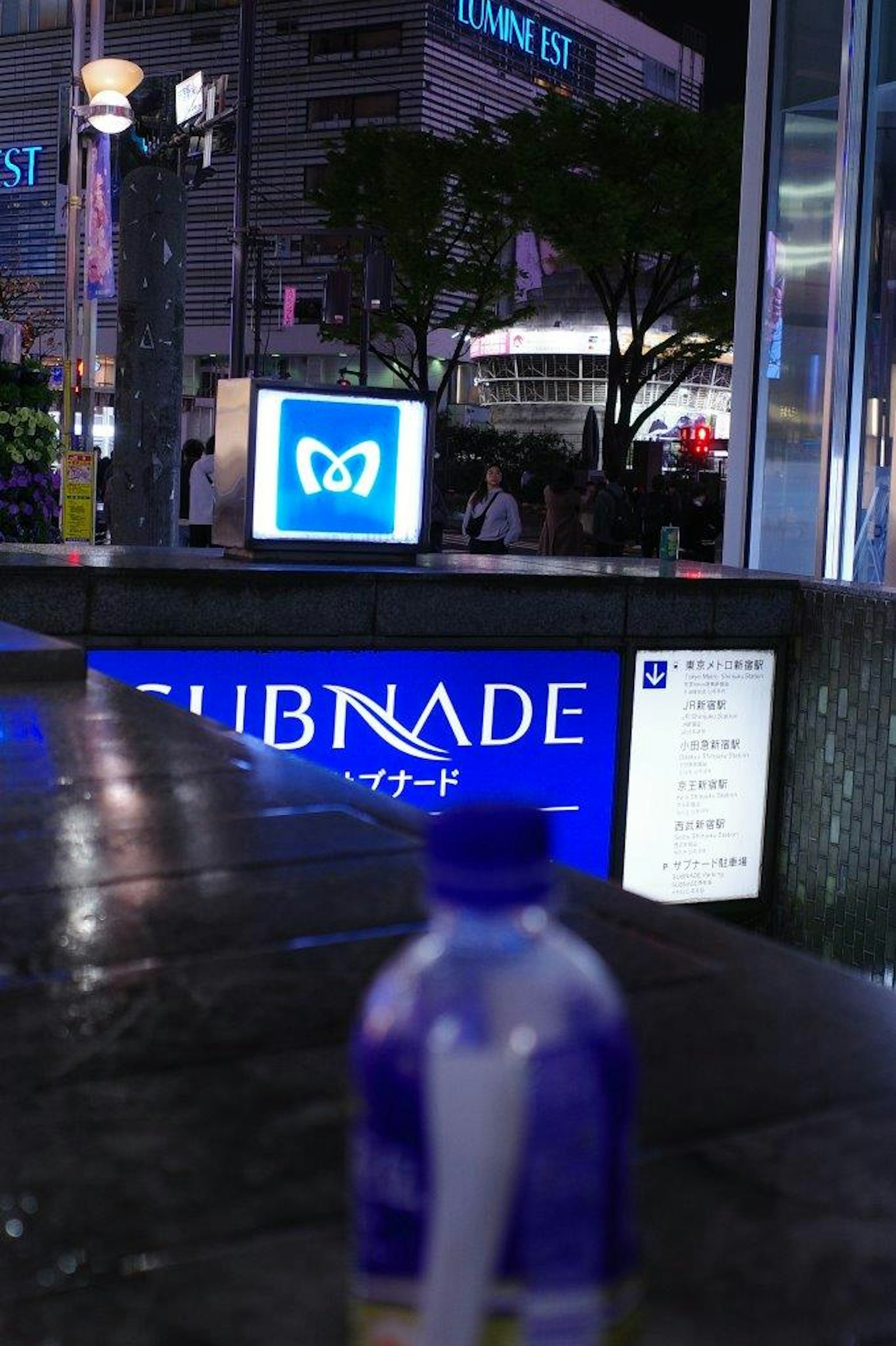 Nachtszene mit dem CLUBNADE-Schild und einer blauen Flasche