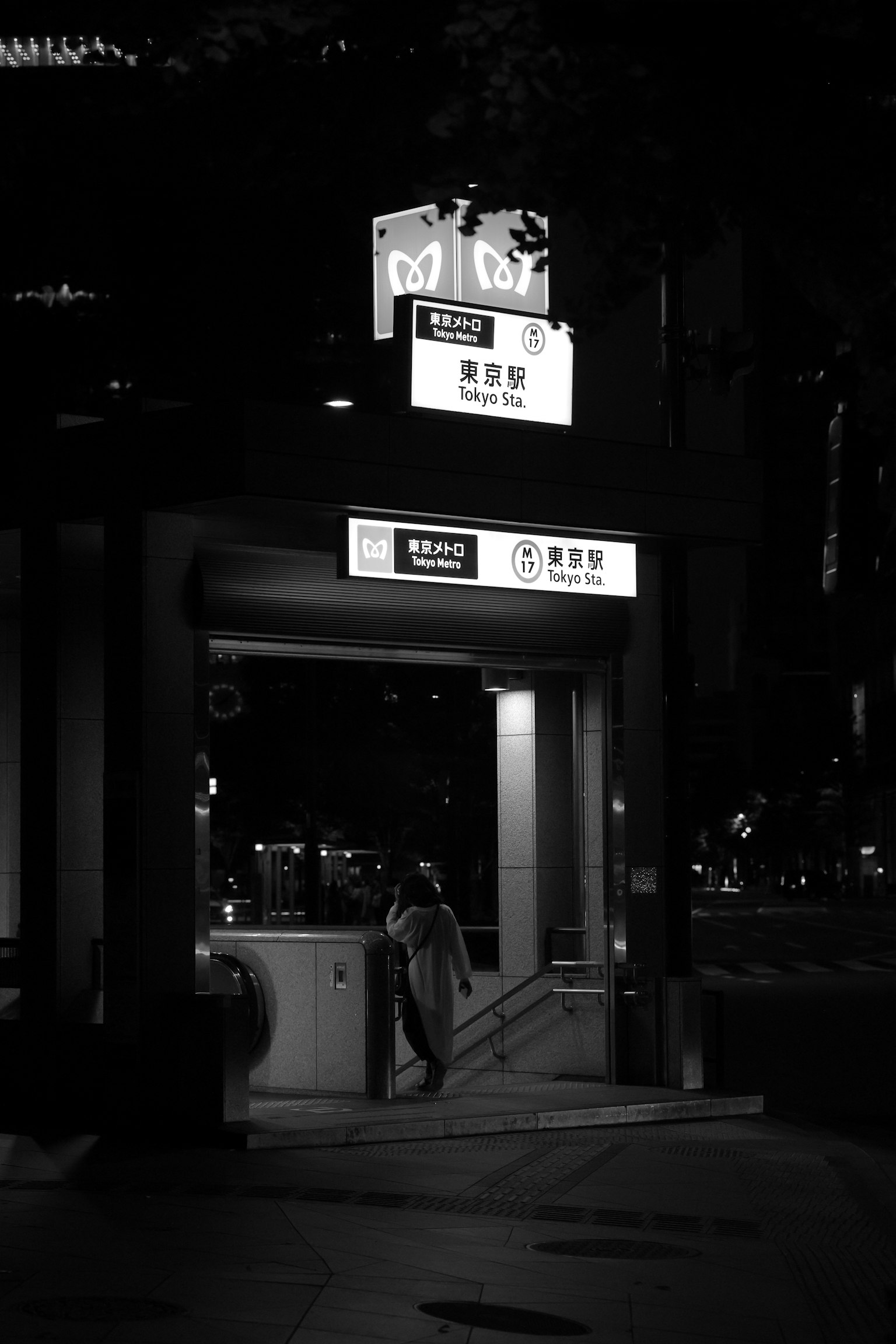 Escena urbana nocturna con la entrada de una estación de metro y señalización en chino iluminada