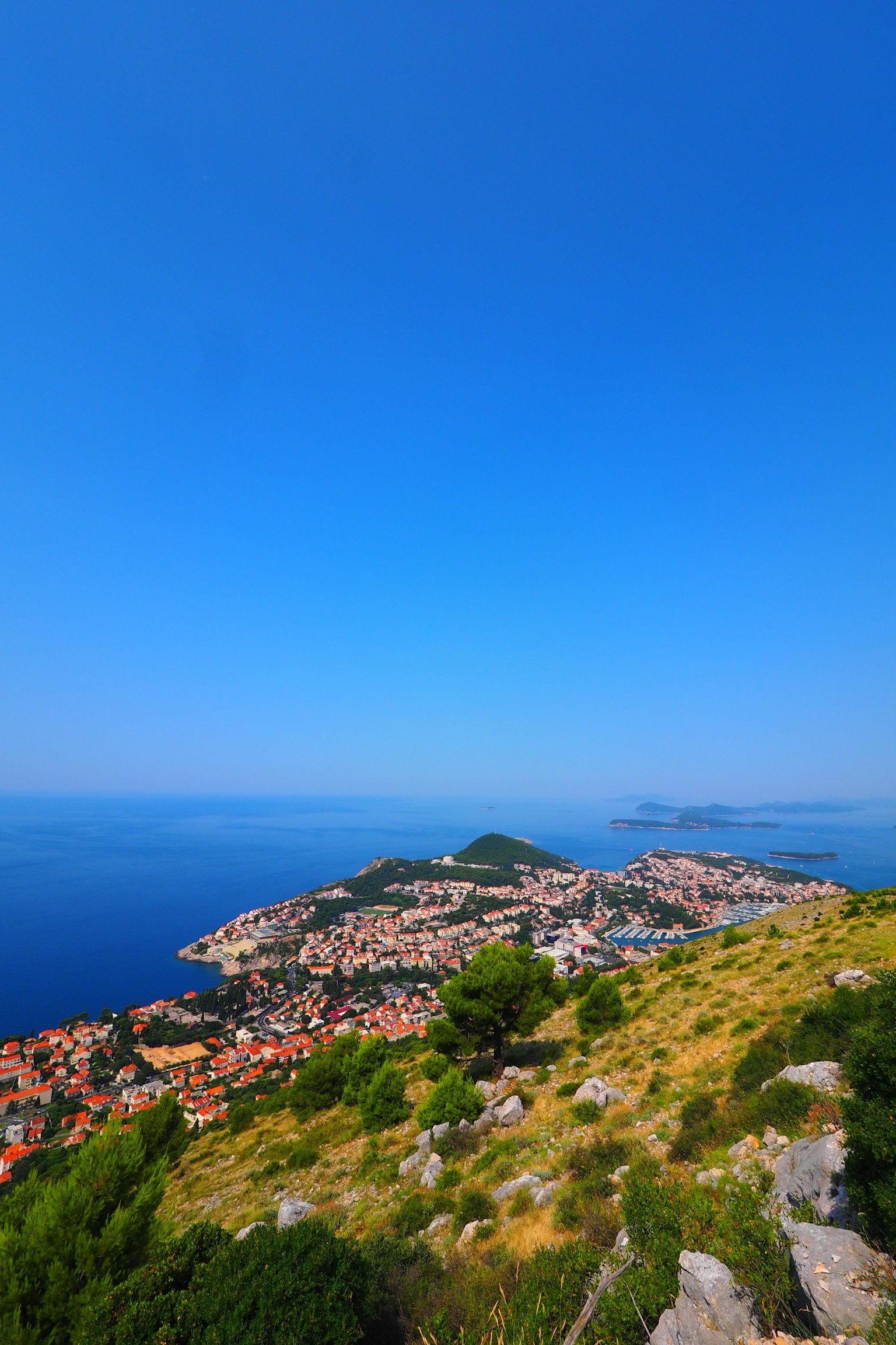 Vista panoramica da una collina con cielo blu vibrante e città costiera