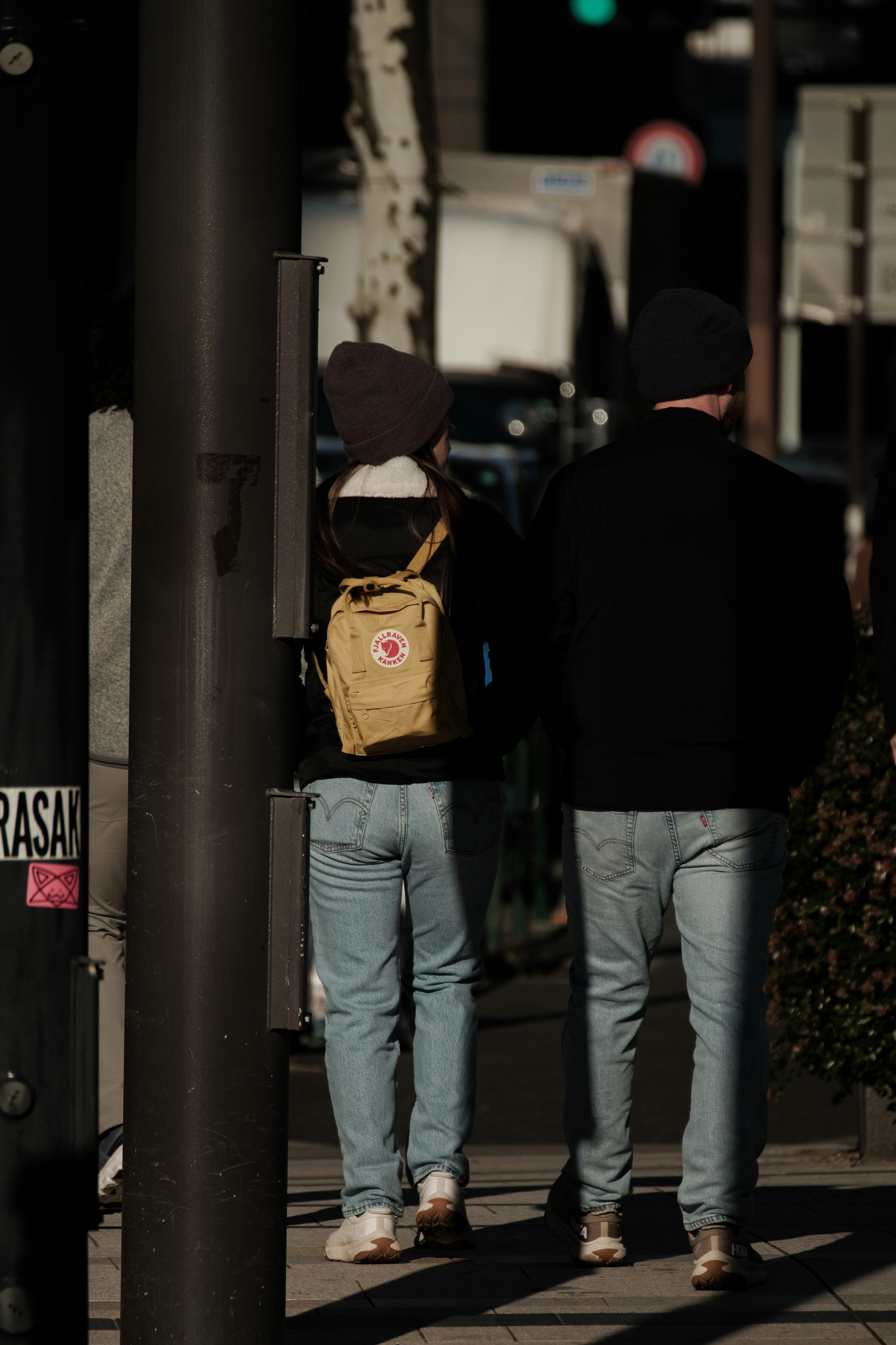 deux personnes vues de dos avec un sac à dos jaune dans une ruelle