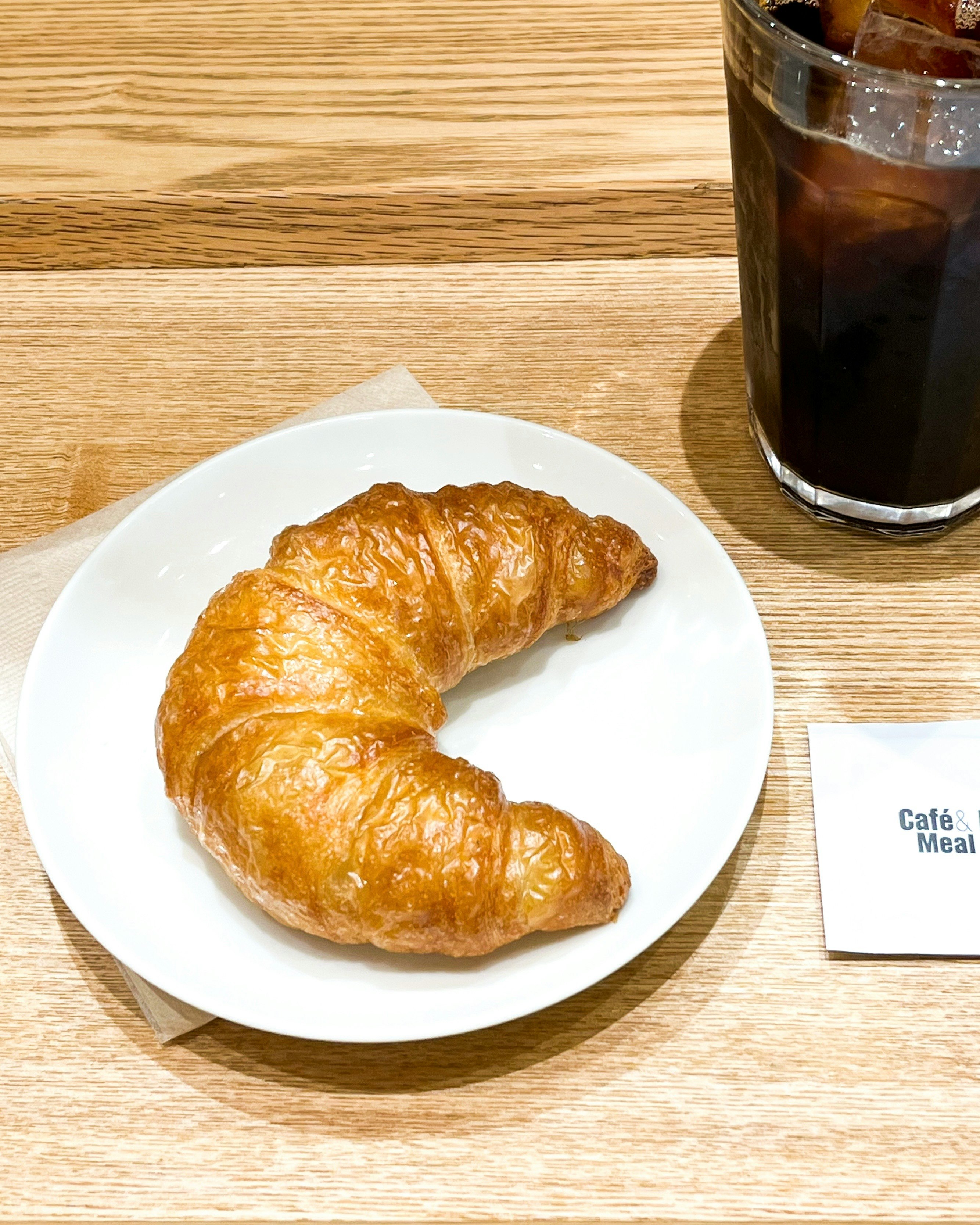 Croissant và cà phê đá trên bàn gỗ