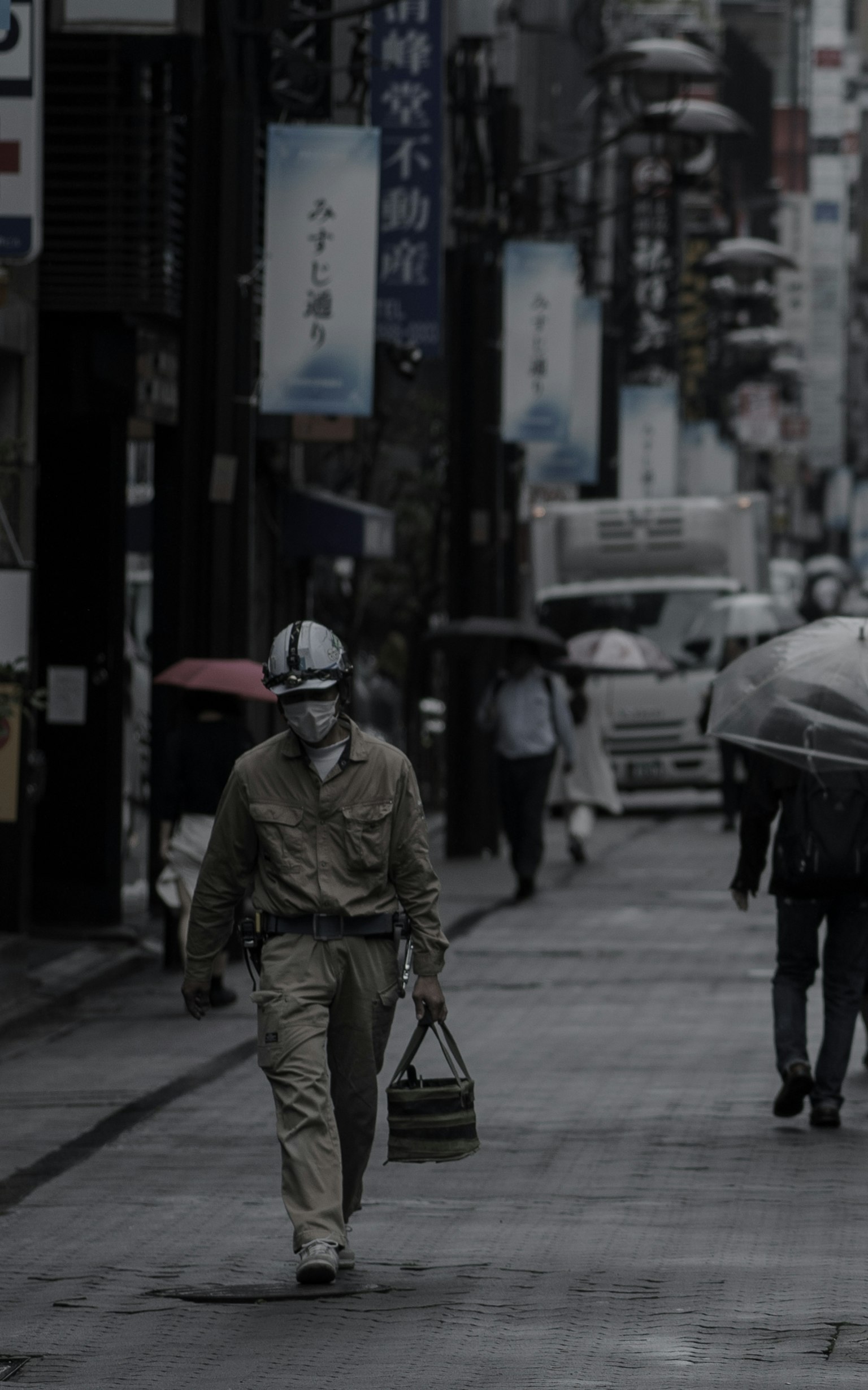 在昏暗街道上行走的工人和撑伞的人们