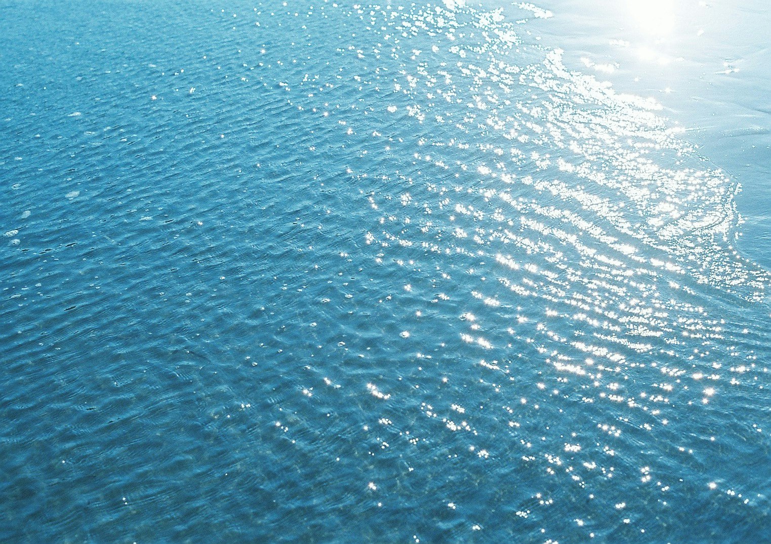 青い海面に反射する太陽光のきらめき