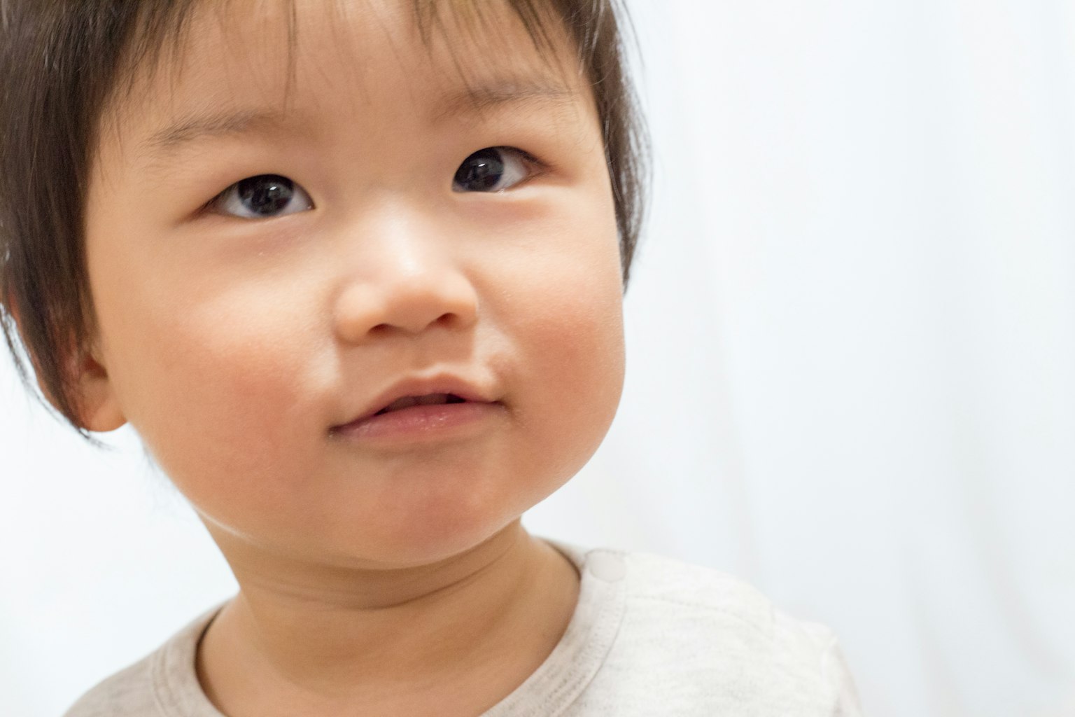 Wajah anak kecil yang tersenyum ke arah kamera