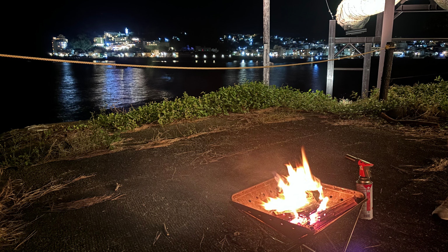夜晚海边的篝火与远处城市的灯光
