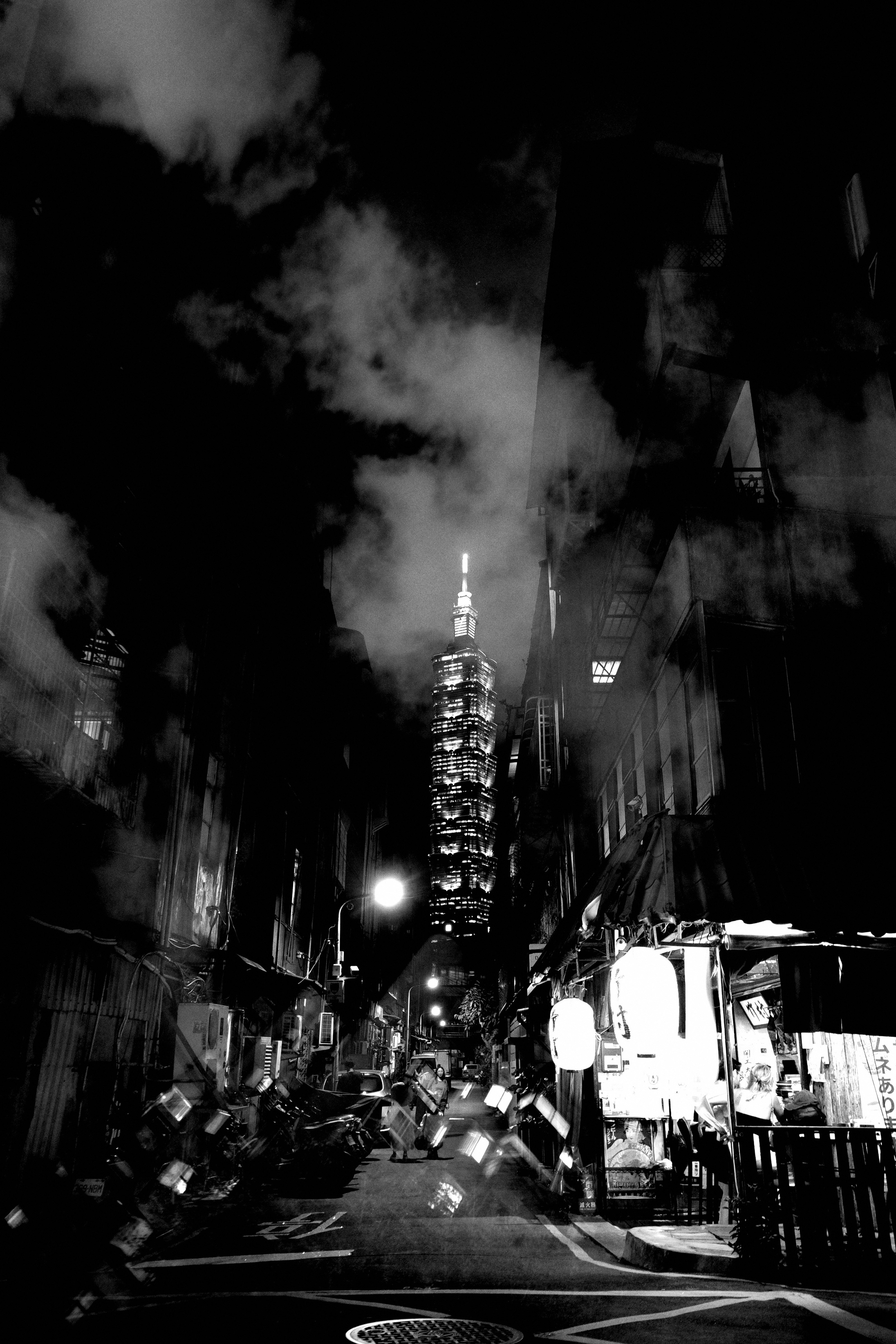 夜の路地にそびえる台北101のモノクロ夜景