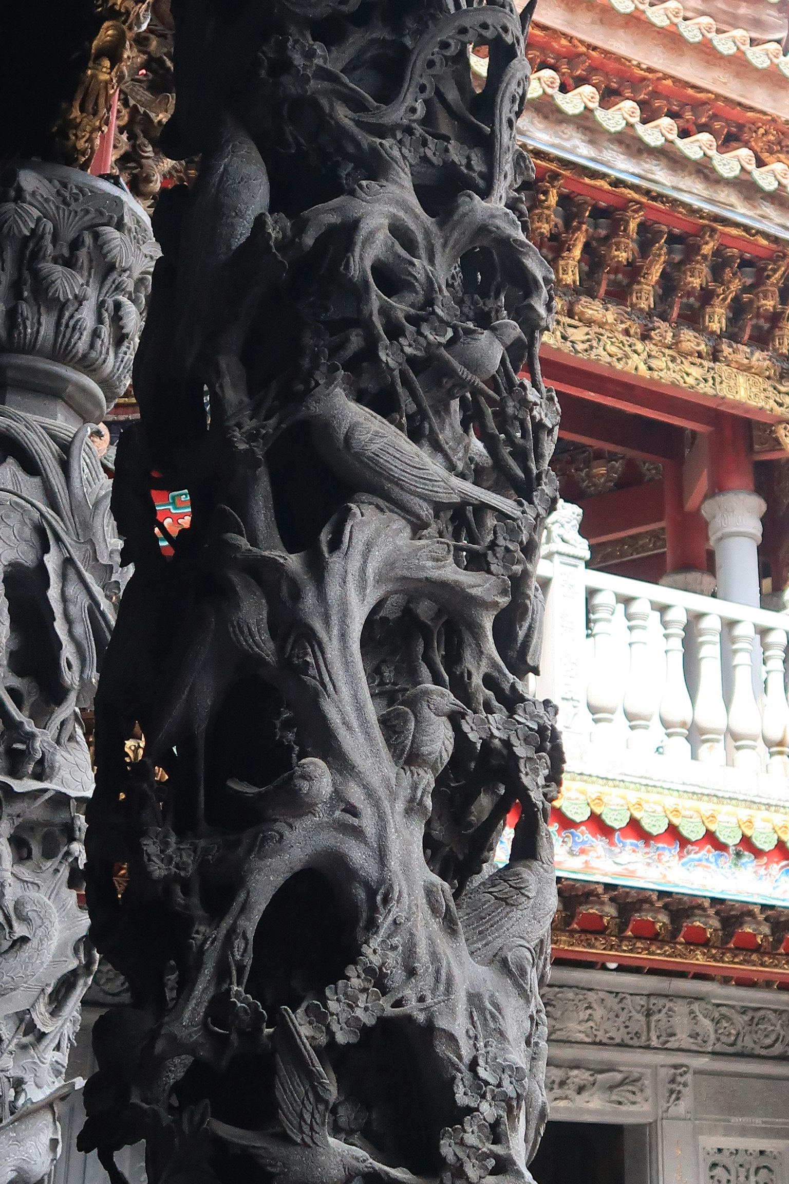 複雜的黑色雕刻柱子與傳統建築背景