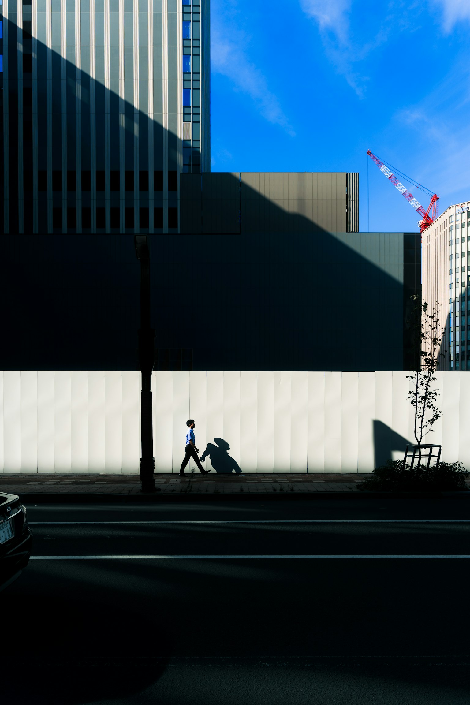 在藍天和建築背景下走路的人的輪廓和自行車