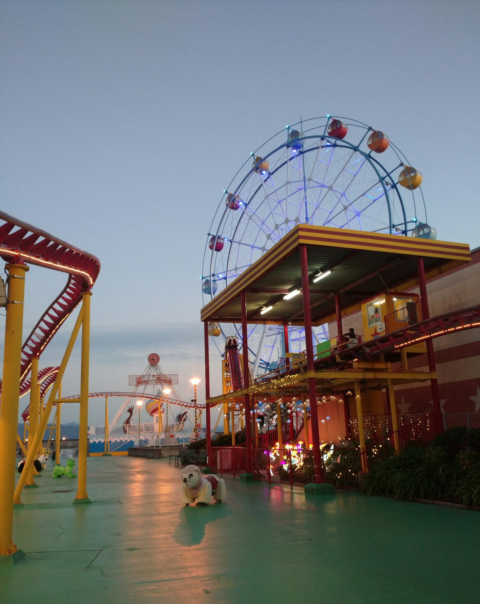 Pemandangan taman hiburan dengan roda ferris berwarna-warni dan atraksi