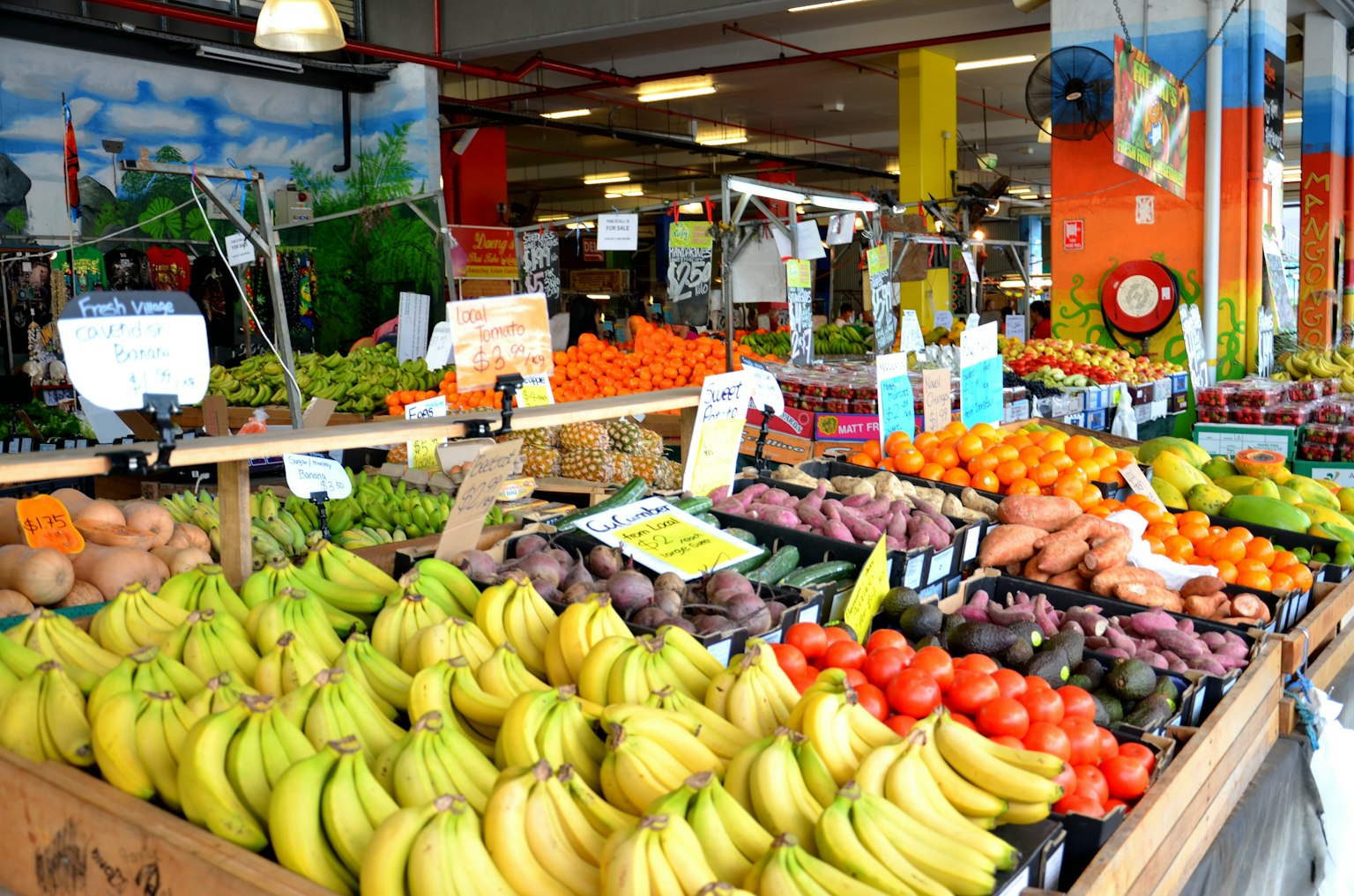 Scena di mercato vivace con vari frutti tra cui banane, pomodori e patate dolci
