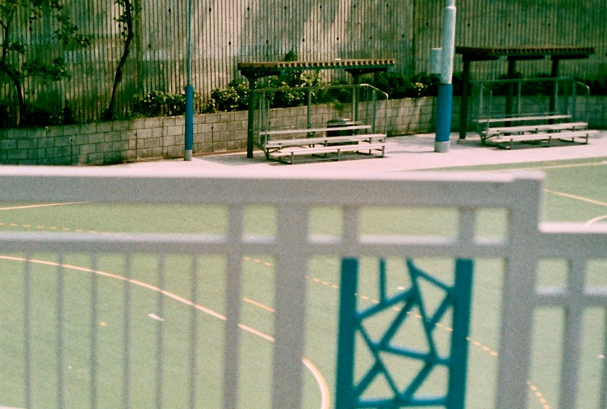 フェンス越しの屋外ベンチと遊具のある公園の通路