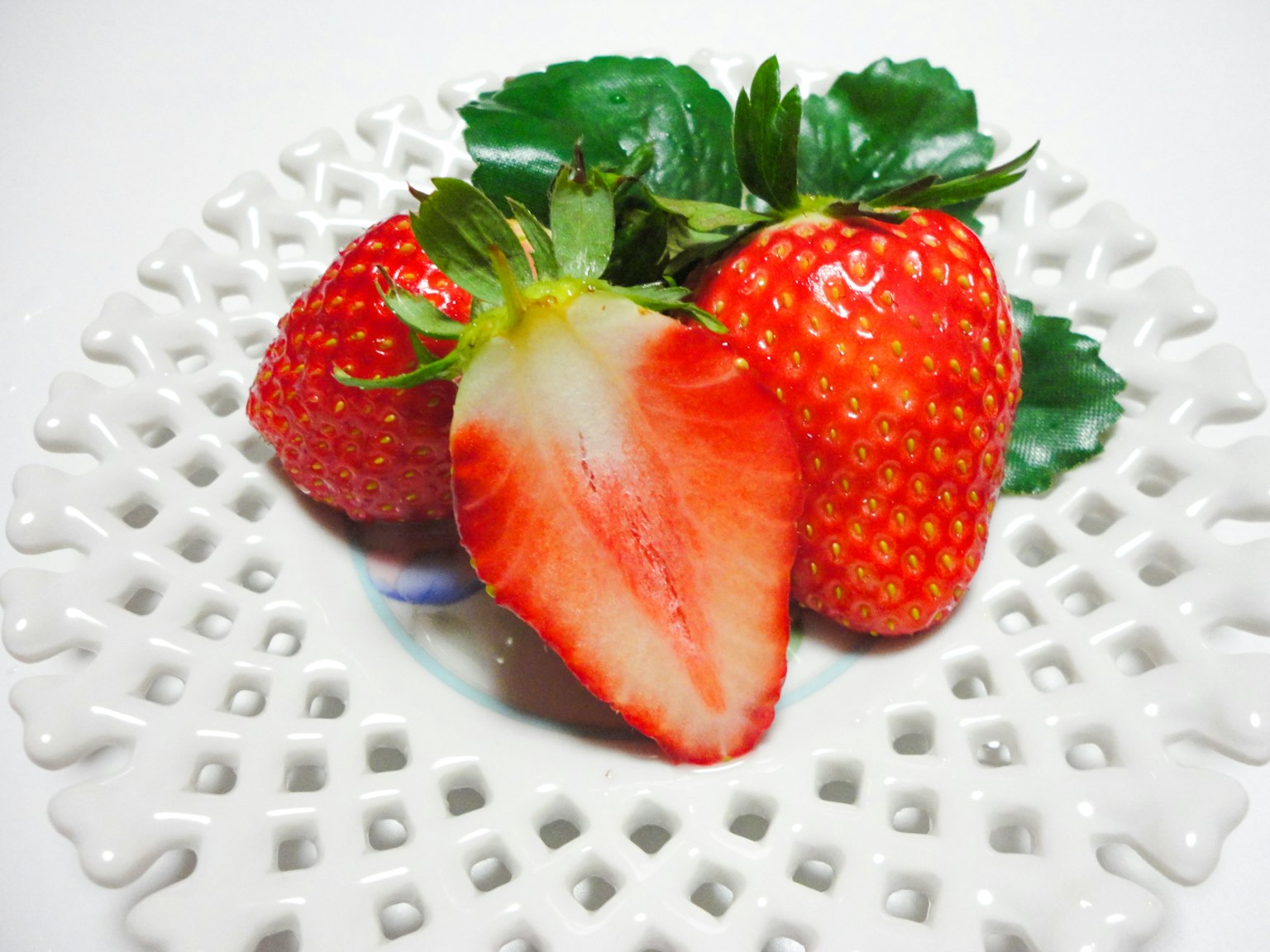 Fresche fragole su un piatto bianco con una tagliata a metà