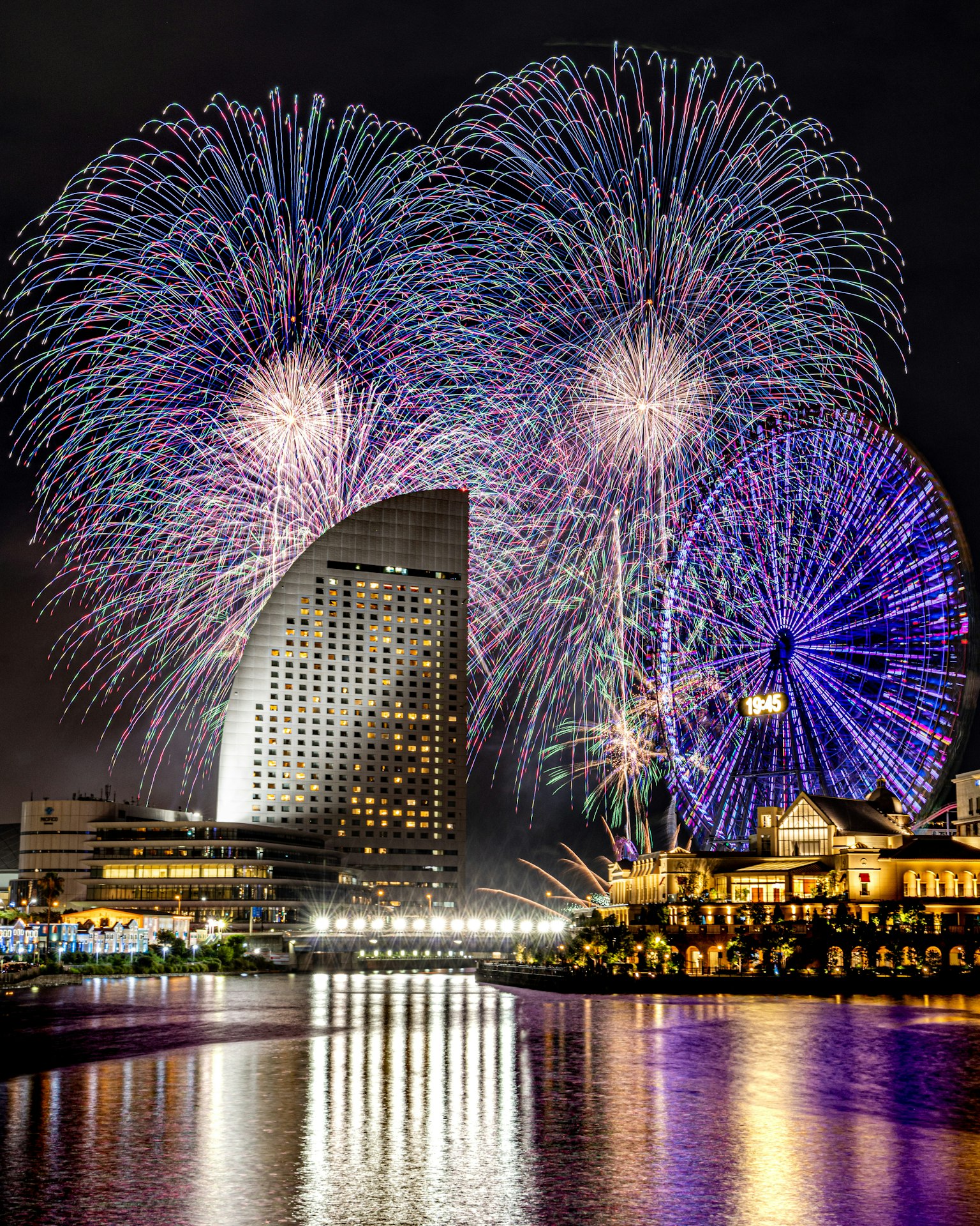Fuegos artificiales coloridos iluminando el cielo nocturno con reflejos en el agua