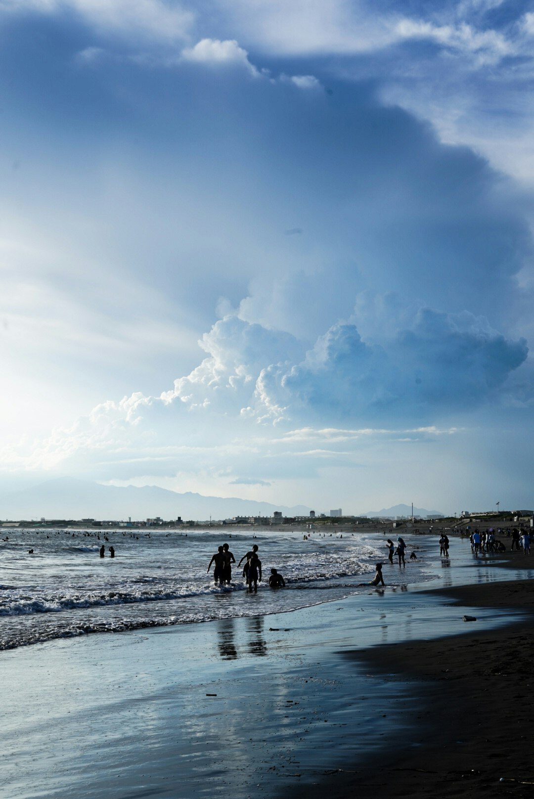 personnes jouant sur le rivage de la plage sous de vastes nuages