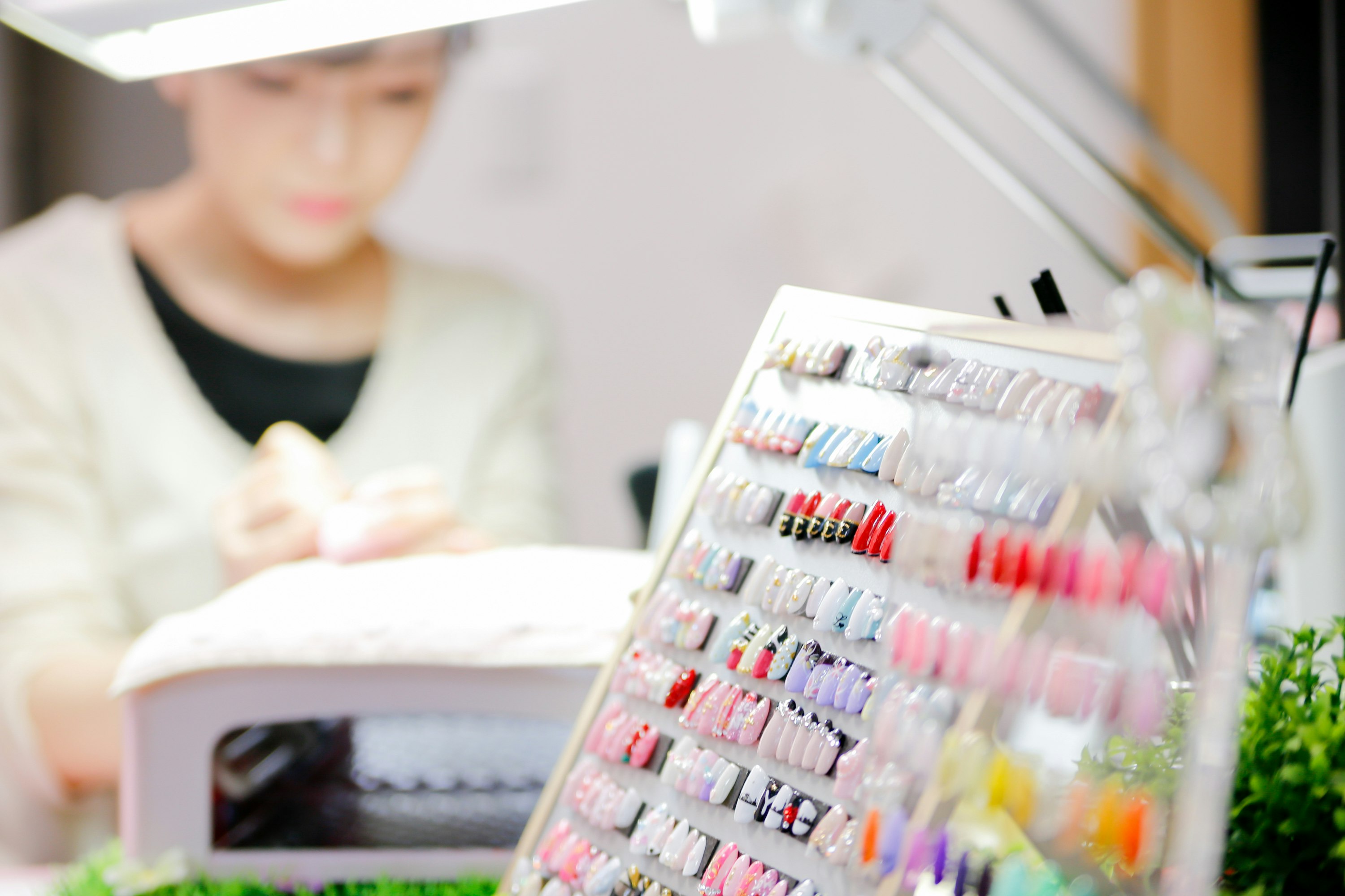 Bảng màu sơn móng tay trong tiệm làm nail với bàn tay đang được chăm sóc