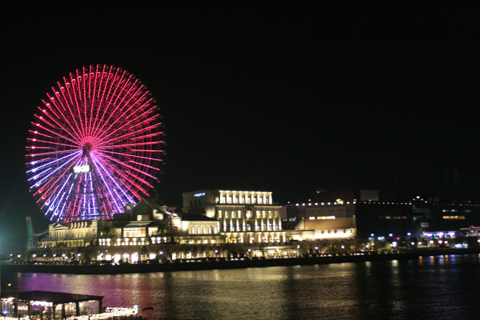 Vue nocturne d'une grande roue et de bâtiments au bord de l'eau