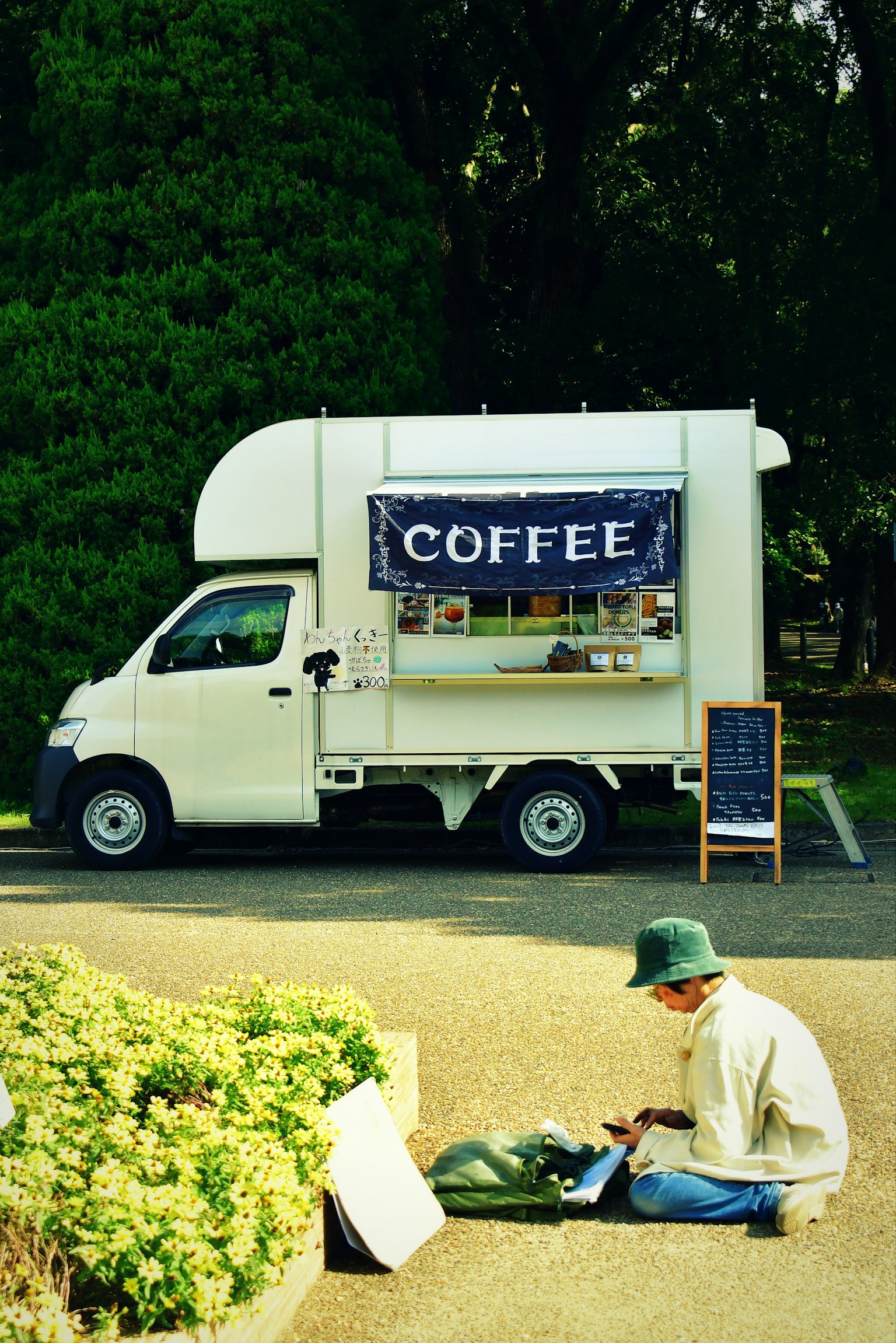 コーヒーのトラックと地面に座っている男性の画像