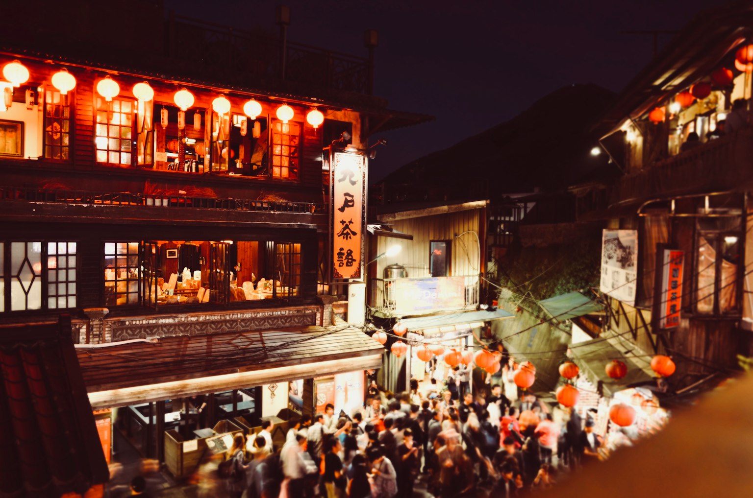 Scène nocturne d'une rue animée avec des lanternes rouges et des foules