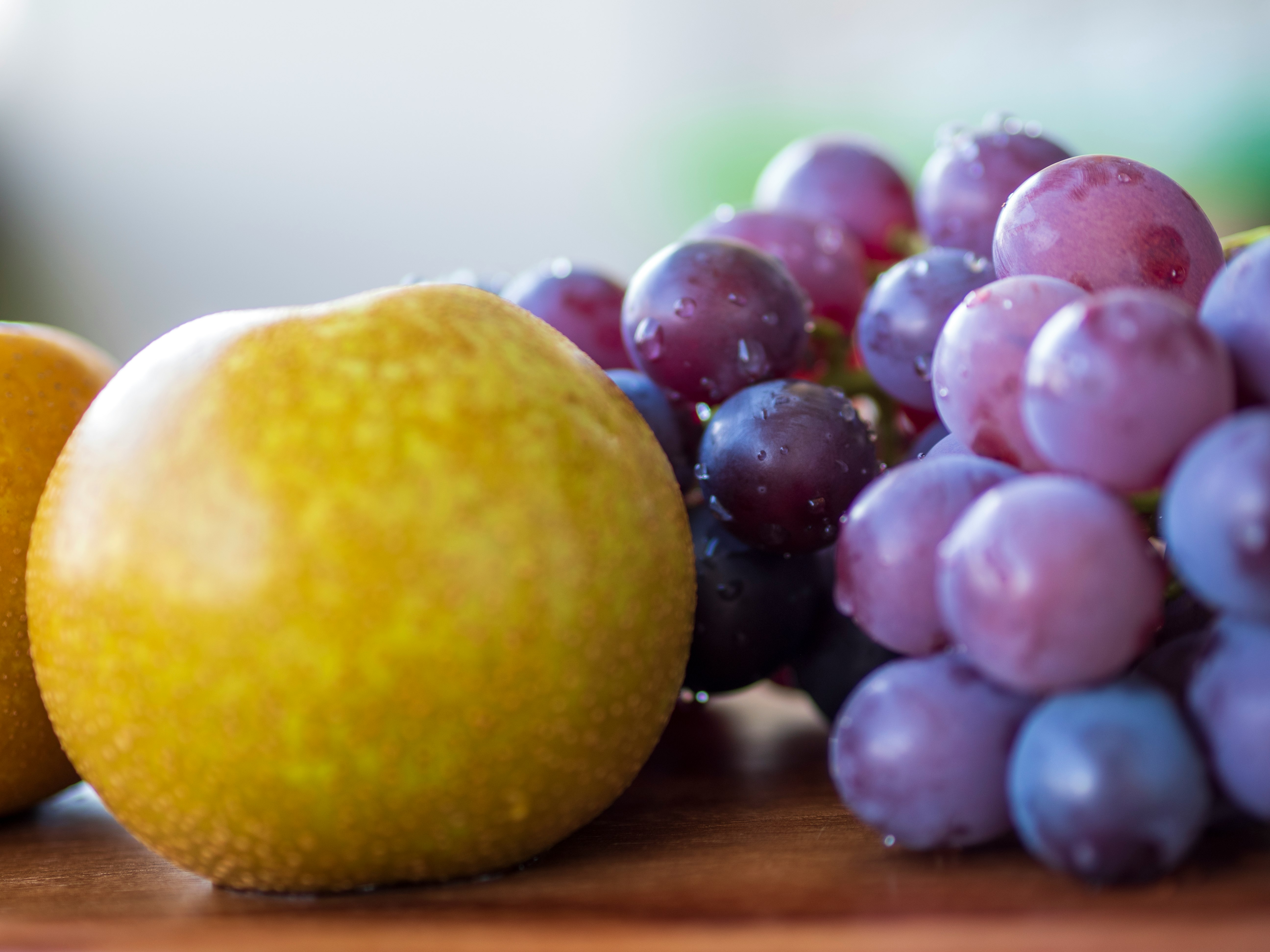 citrus fruit and grapes on a wooden cutting board
